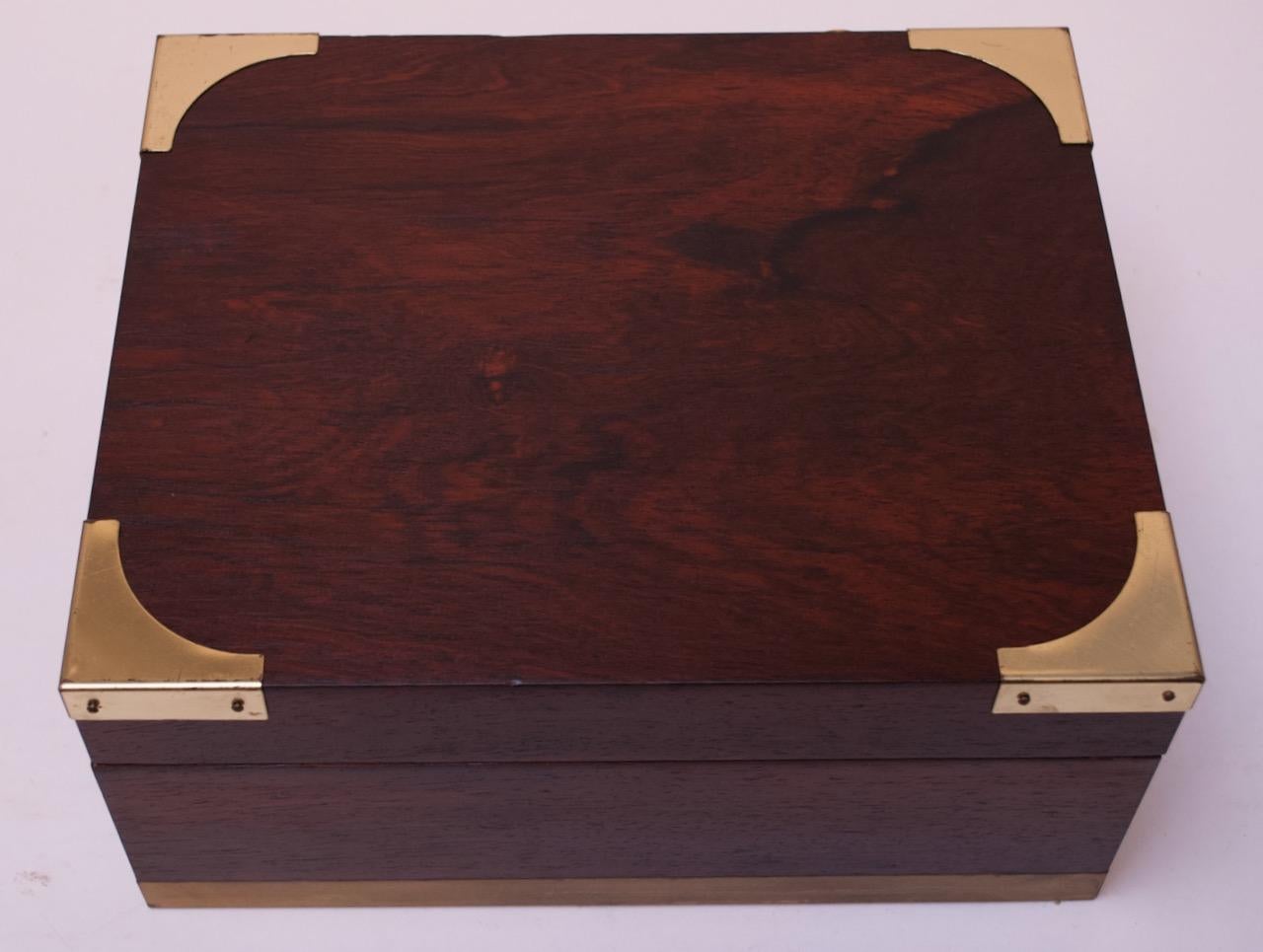 Elegant humidor veneered in rosewood with brass corner and hinged detail. Interior is solid Spanish Cedar, the ideal wood for cigar storage, as it is not prone to warping, can repel tobacco beetles, and holds more moisture than most woods, allowing