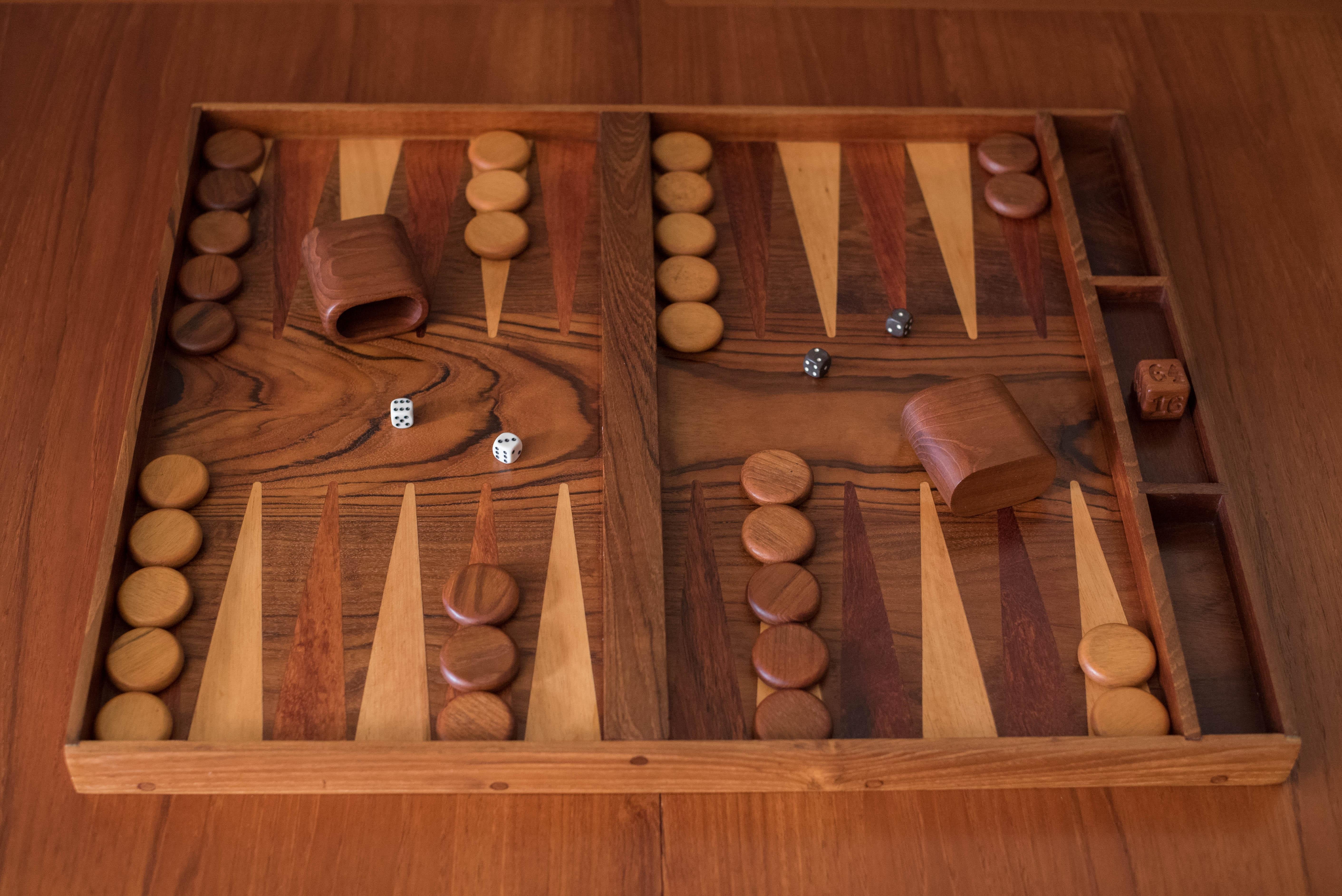 Vintage backgammon board game set circa 1970's in walnut and teak. Features a stunning contrast of rosewood and maple inlaid points. This set is complete with 2 pairs of dice, 1 teak doubling cube, 2 teak cups, and 30 checkers in teak and maple.