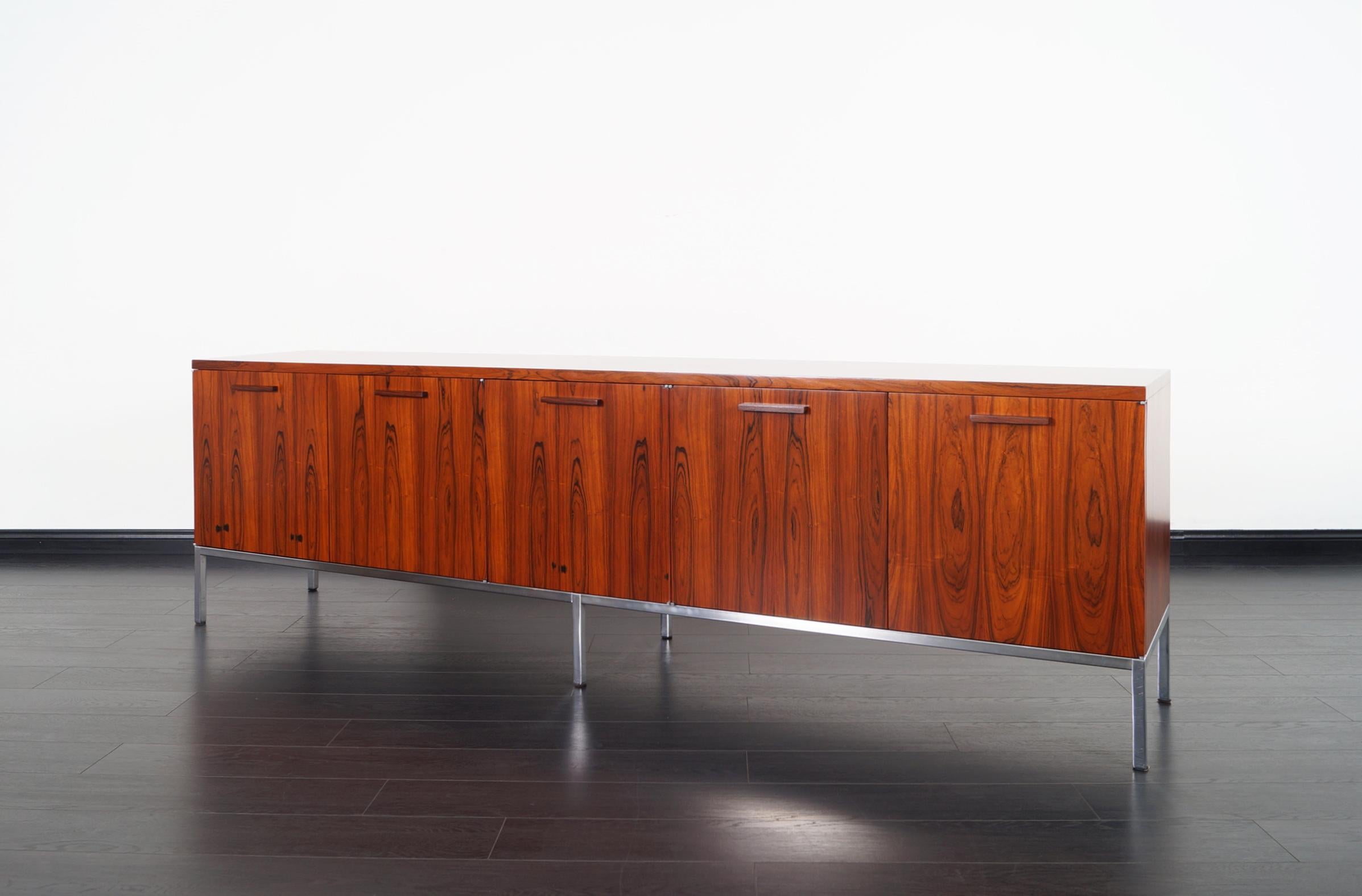 Monumental Brazilian rosewood credenza attributed to Florence Knoll. Features stunning Brazilian rosewood, five doors concealing four adjustable shelves, and three pull out drawers.