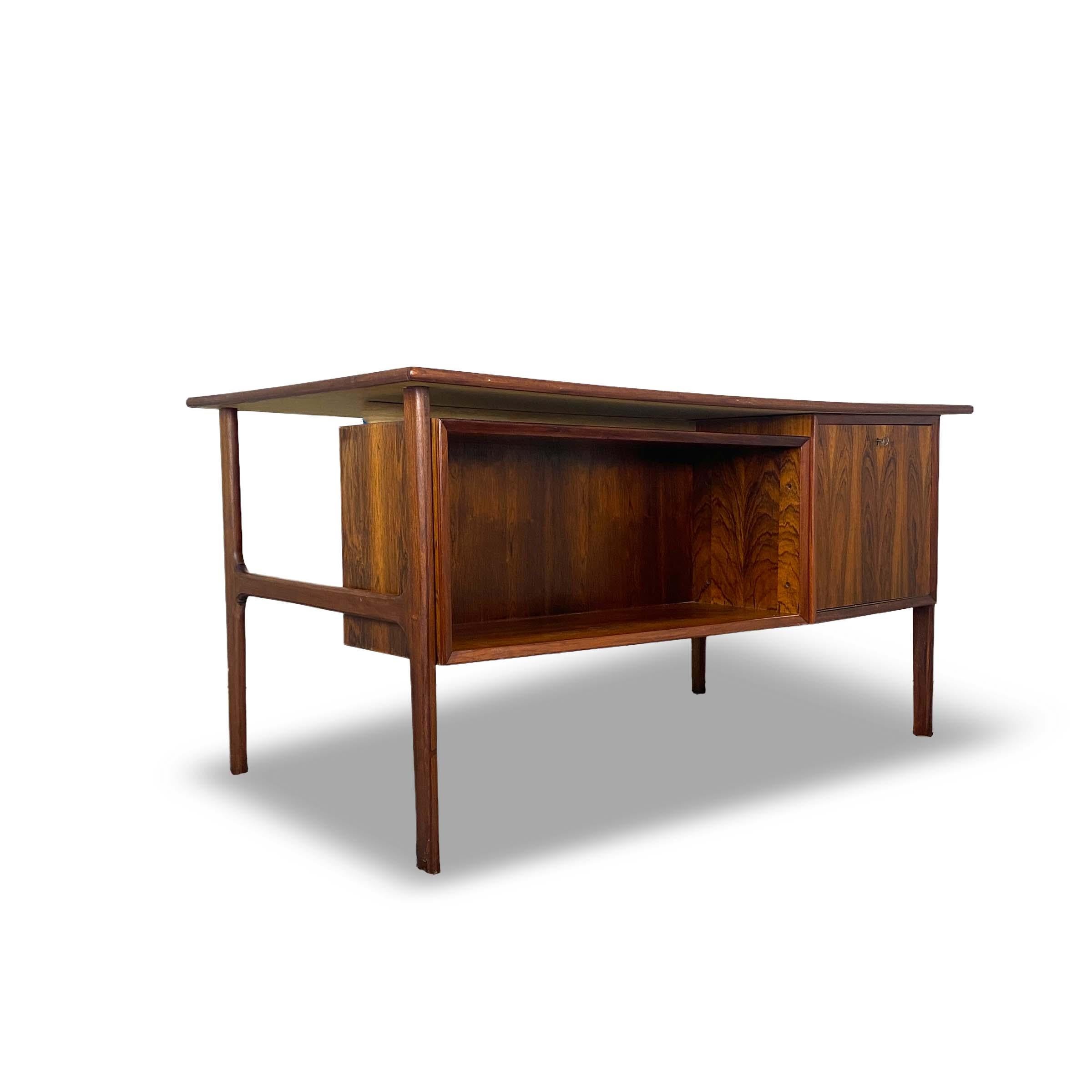 Condition: Great Vintage Condition

Dimensions: 55” L x 32.25” D x 28.5” H (28” H Leg Room, 33” L Leg Room)

Description: Gorgeously designed Danish rosewood desk. Made in Denmark, circa 1960s. Door in back drops down for bar access. Keys included.