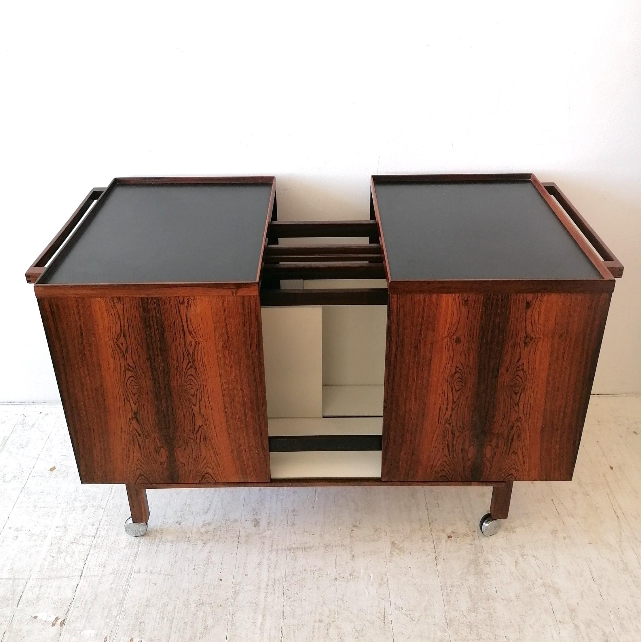 Mid century rosewood expanding drinks trolley / bar cart by Niels-Erik Glasdam Jensen for Vantinge Mobelindustri, Denmark 1960s. Divided inset black laminate top. Inside are sliding white compartments and a glass shelf.
Overall great condition-