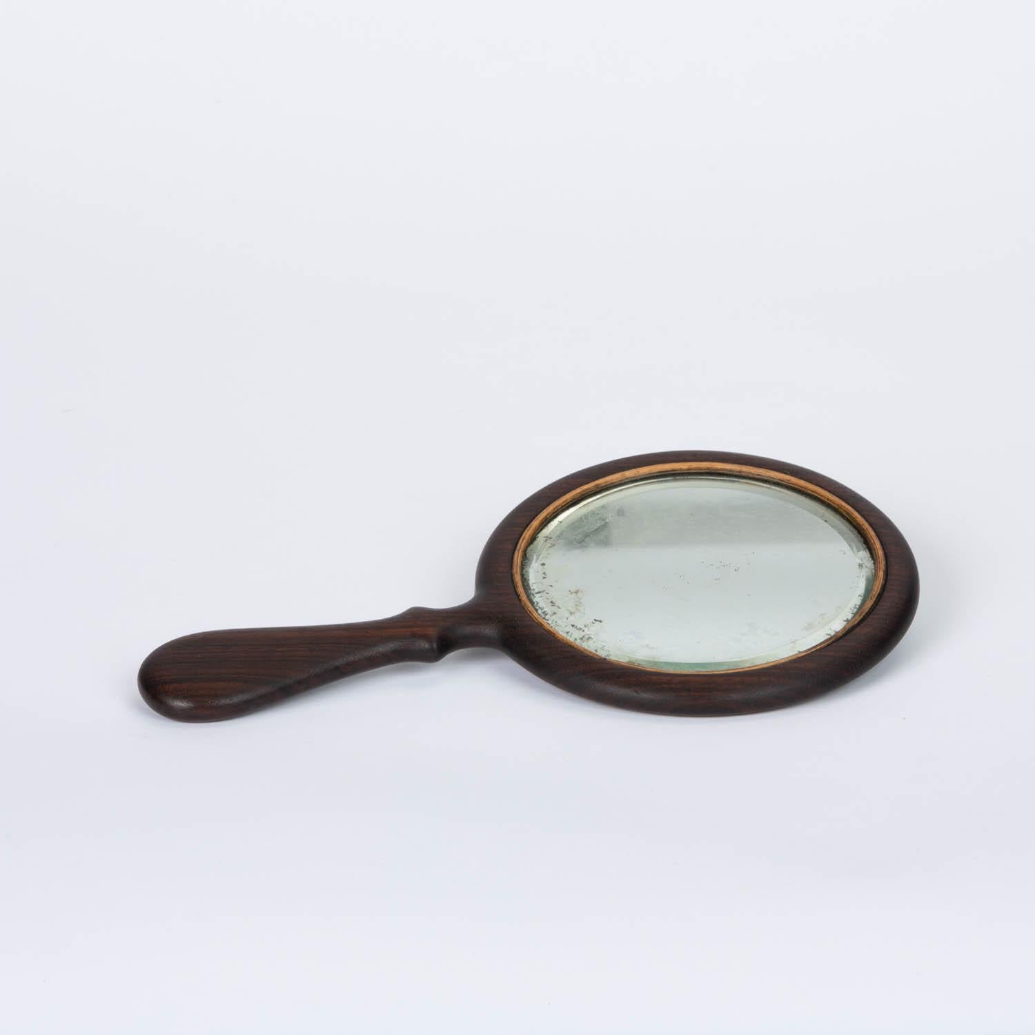 Vintage hand mirror featuring a patinated rosewood handle and frame and antiqued oxidation to the mirror glass.

Condition: Excellent Vintage condition, professionally refinished, age appropriate wear on wood finish and glass.

Measures: 5.25”