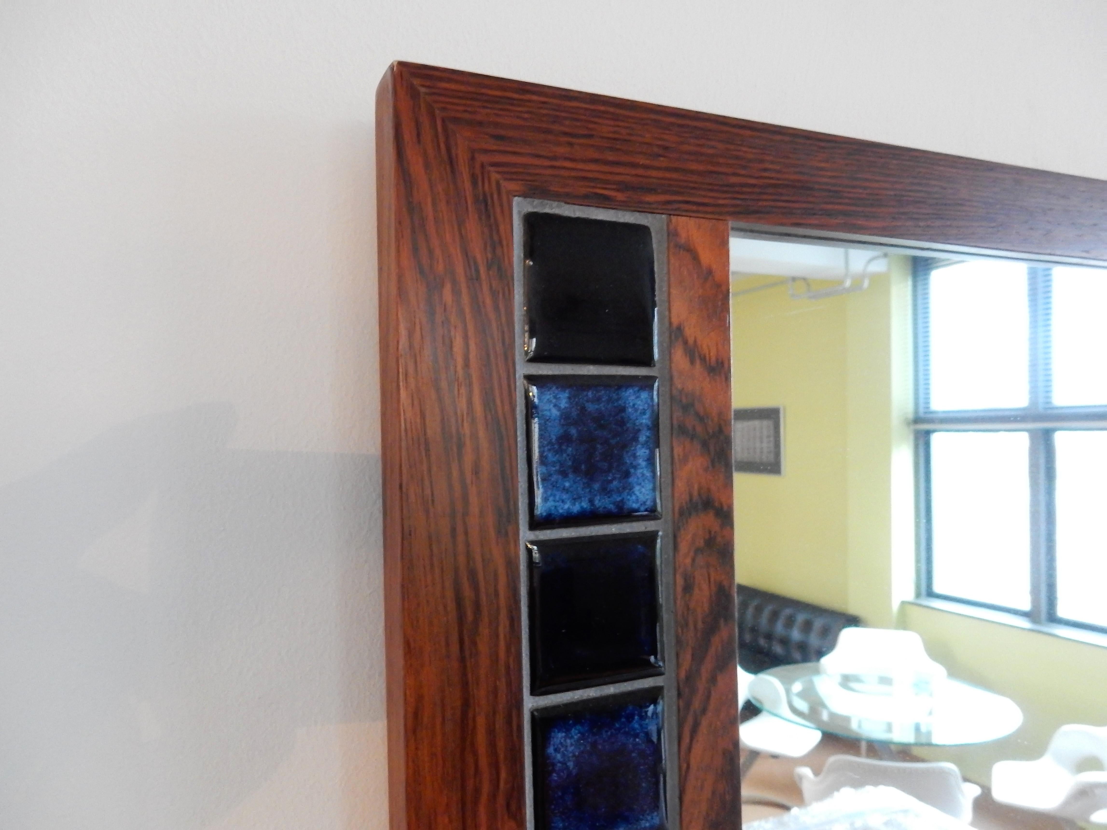 This stunning Danish wall mirror has a rectangular rosewood frame with beautiful inlaid blue tiles. It is in a very good condition with minor signs of age and use.