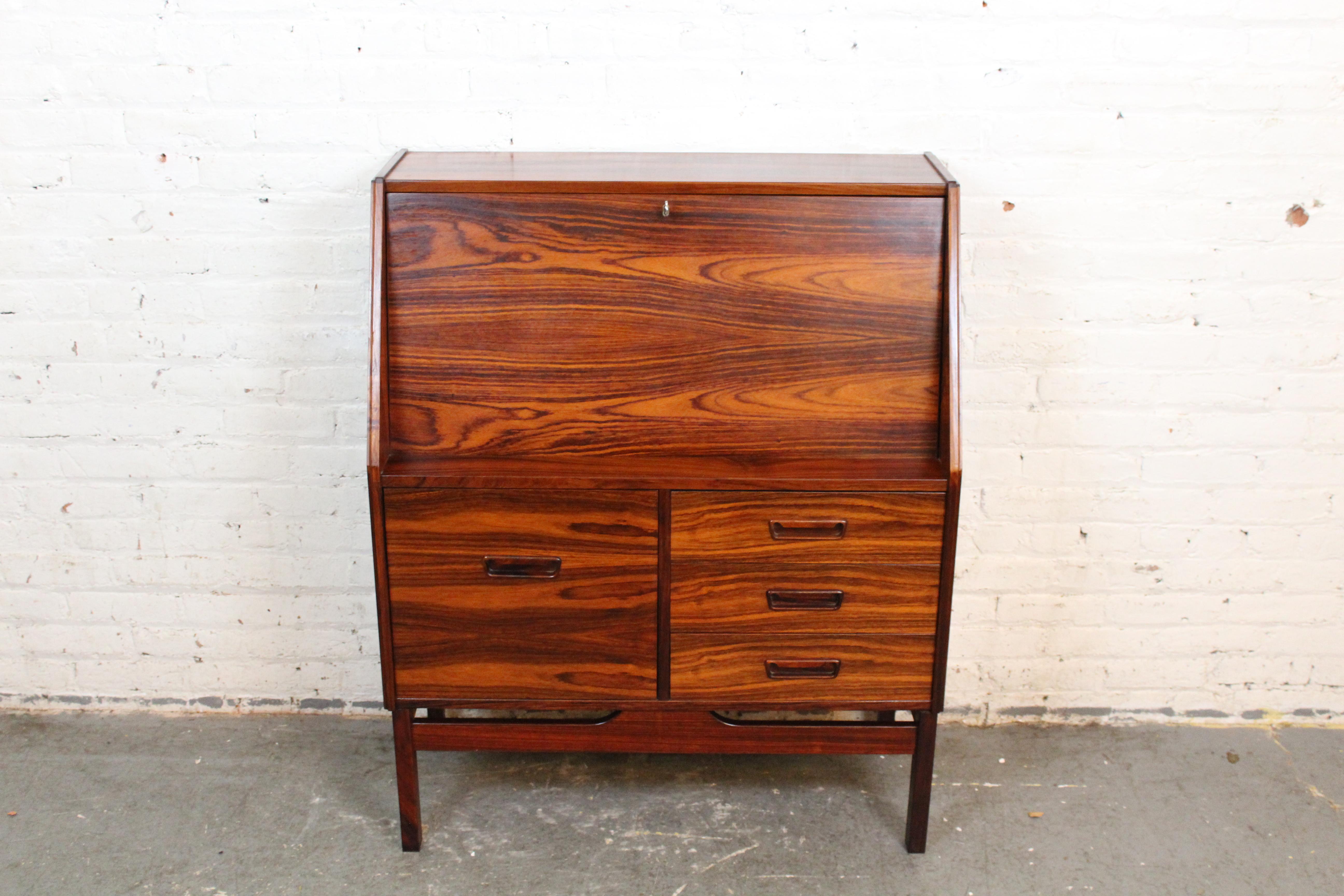 Discover a tranquil workspace with this elegant mid-century Danish Modern secretary desk produced by Dyrlund of Denmark. Constructed with stunning and generous rosewood veneer, this piece packs natural beauty and modern functionality into a compact