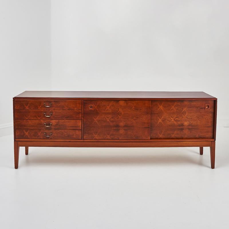 Un exquisito aparador de palisandro de mediados del siglo XX diseñado por Robert Heritage para Archie Shine, hacia 1960. Conocida por su excepcional artesanía y su diseño atemporal, esta pieza es un impresionante ejemplo de mueble modernista