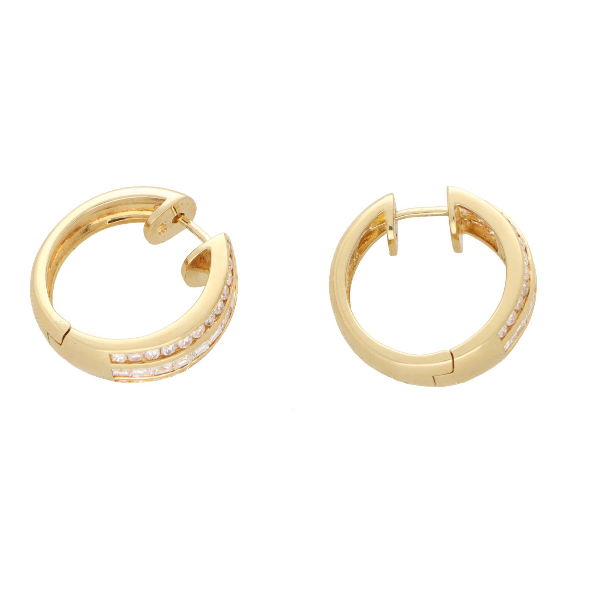 A sparkly pair of diamond hoop earrings set in 18k yellow gold.

Each hoop earring is centrally set with a channel set princess cut diamond panel which is sided by a row of channel set round brilliant cut diamonds. The pairing of the two cuts of