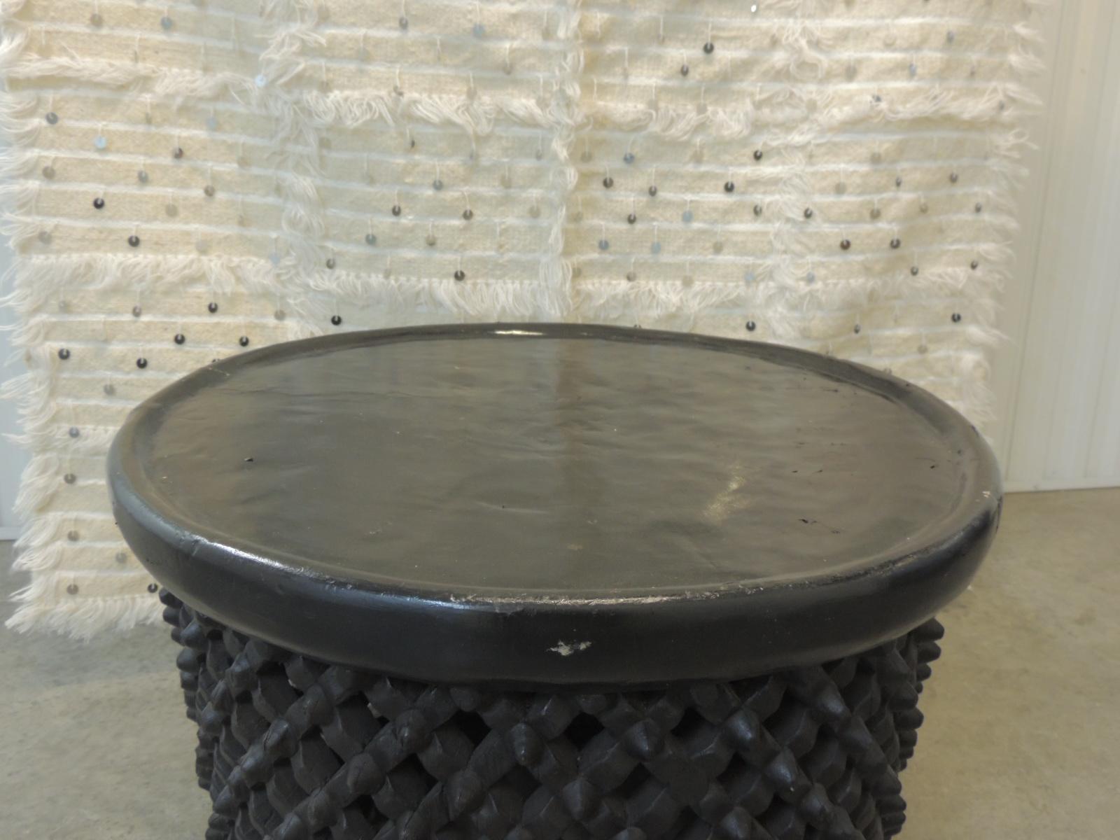 Vintage round black hand carved African round coffee table.
African table from the Bemileke tribe of Cameroon.
Can be use as a Drum table, side table, ottoman.
Hand-carved lattice work in the center, rounded edges.
Size: 23.5 