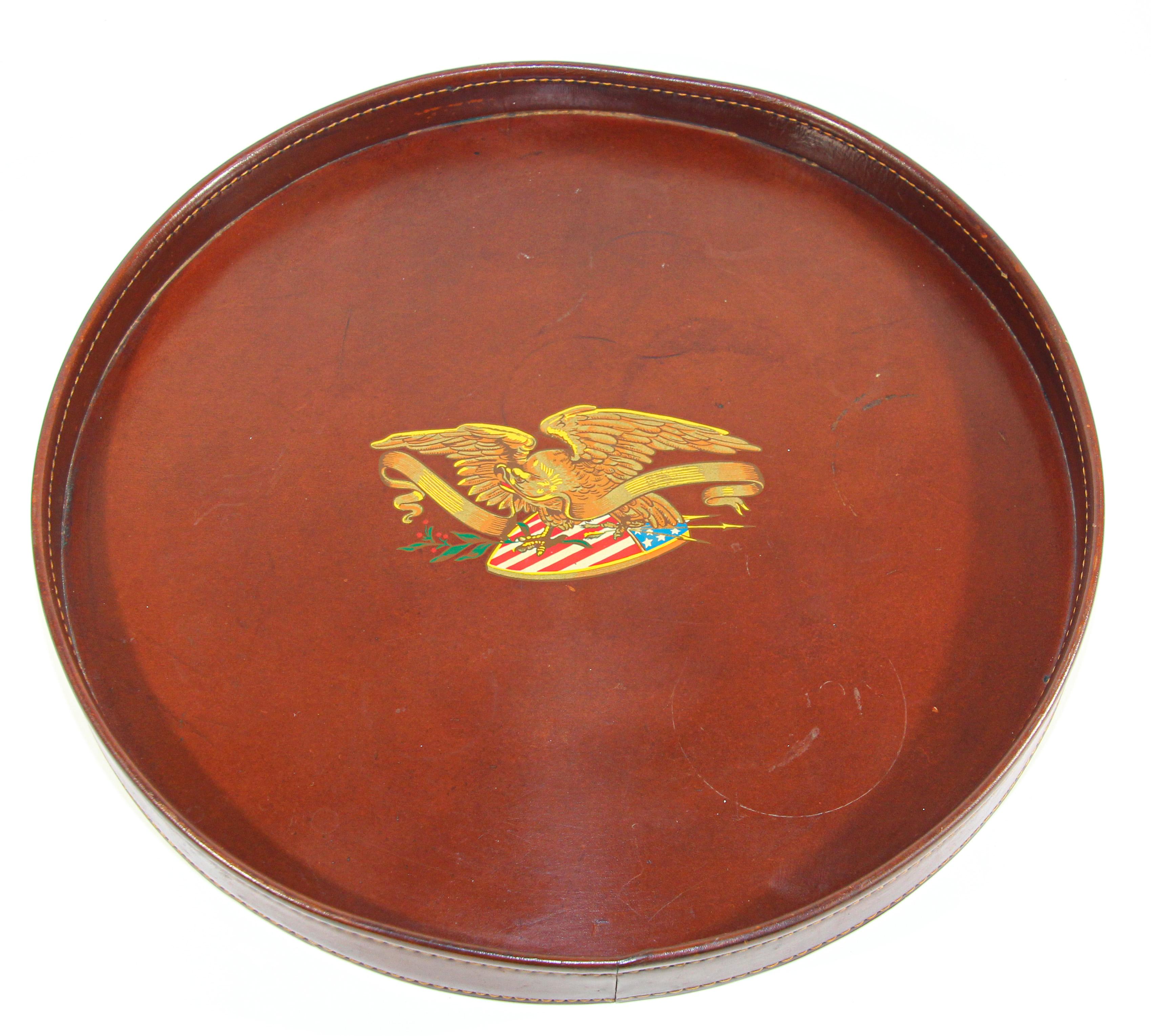 Small vintage round brown leather tray hand painted in the middle with the Bald Eagle carrying the American Flag.
Vintage handcrafted leather tray with the patriotic American motif with hand-stitched along the sides of the tray.
A timeless design