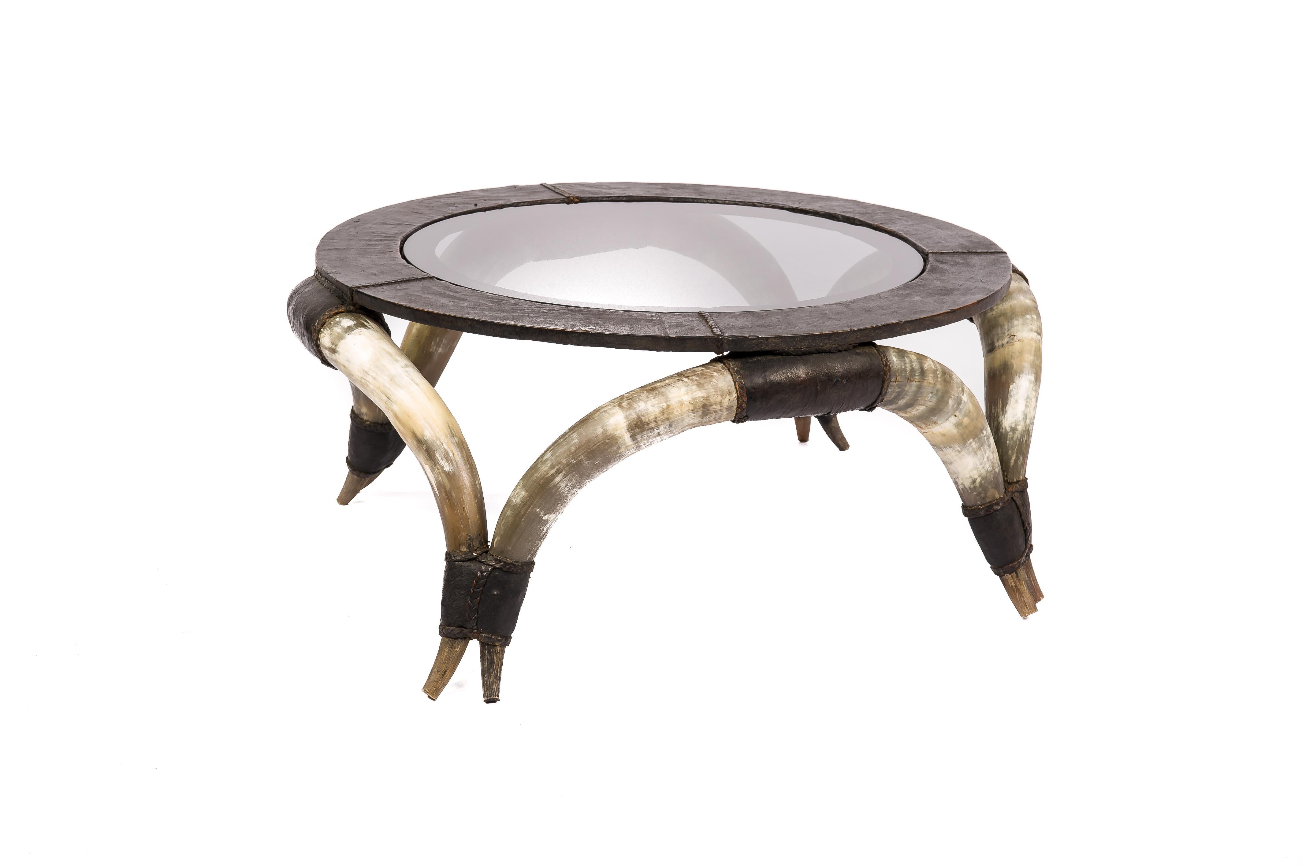 This exceptionally beautiful vintage coffee table had a circular top with an inlaid smoked glass panel. The wood is covered with matt black leather. The seems were covered with braided leather ribbons. The coffee table's top sits on 8 connected
