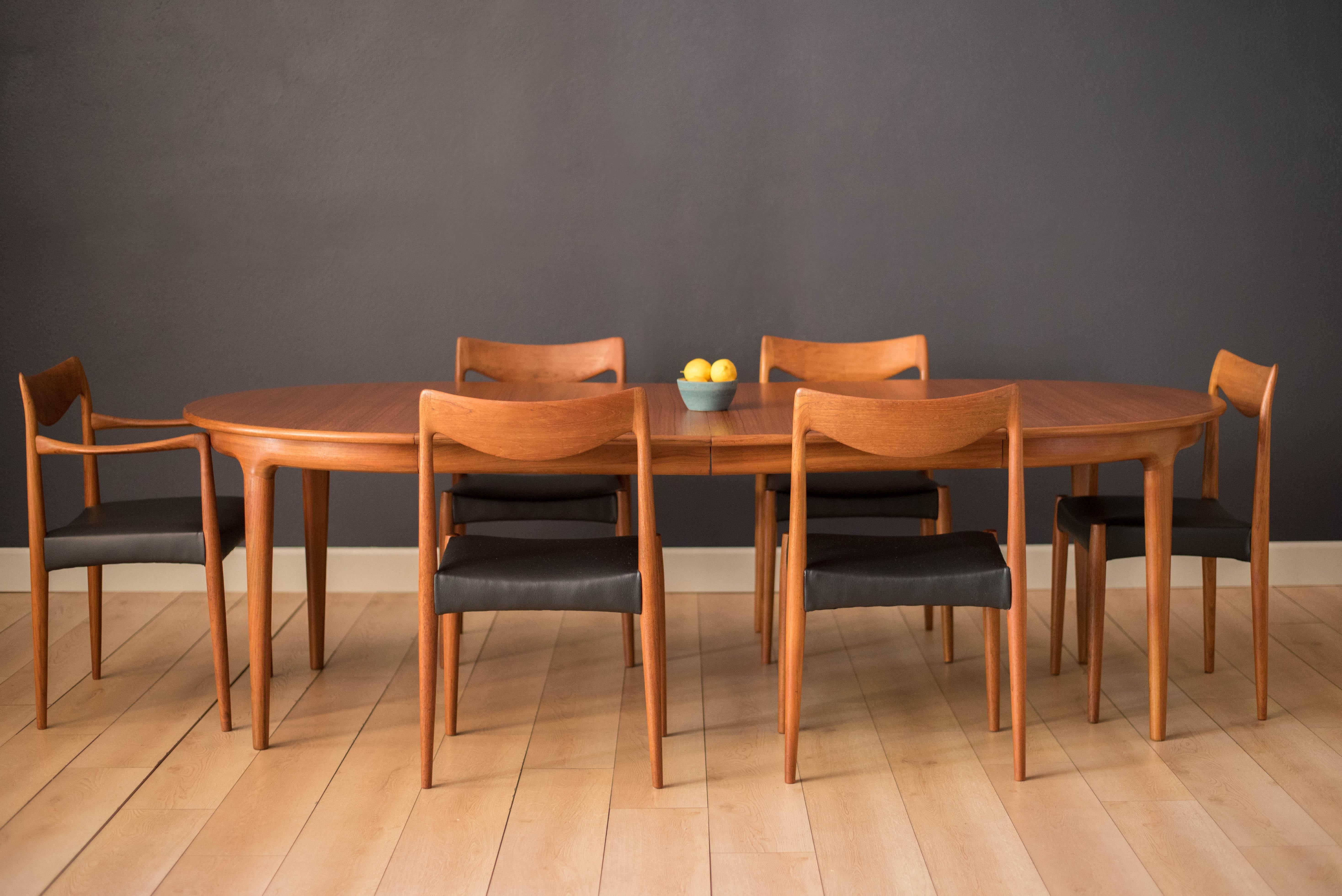 Mid Century circular dining table designed by Johannes Andersen for Uldum Møbelfabrik. This piece displays continuous teak grains and solid edge banding with a seamless sculpted apron. Includes two separate leaves that extend to an oval tabletop to