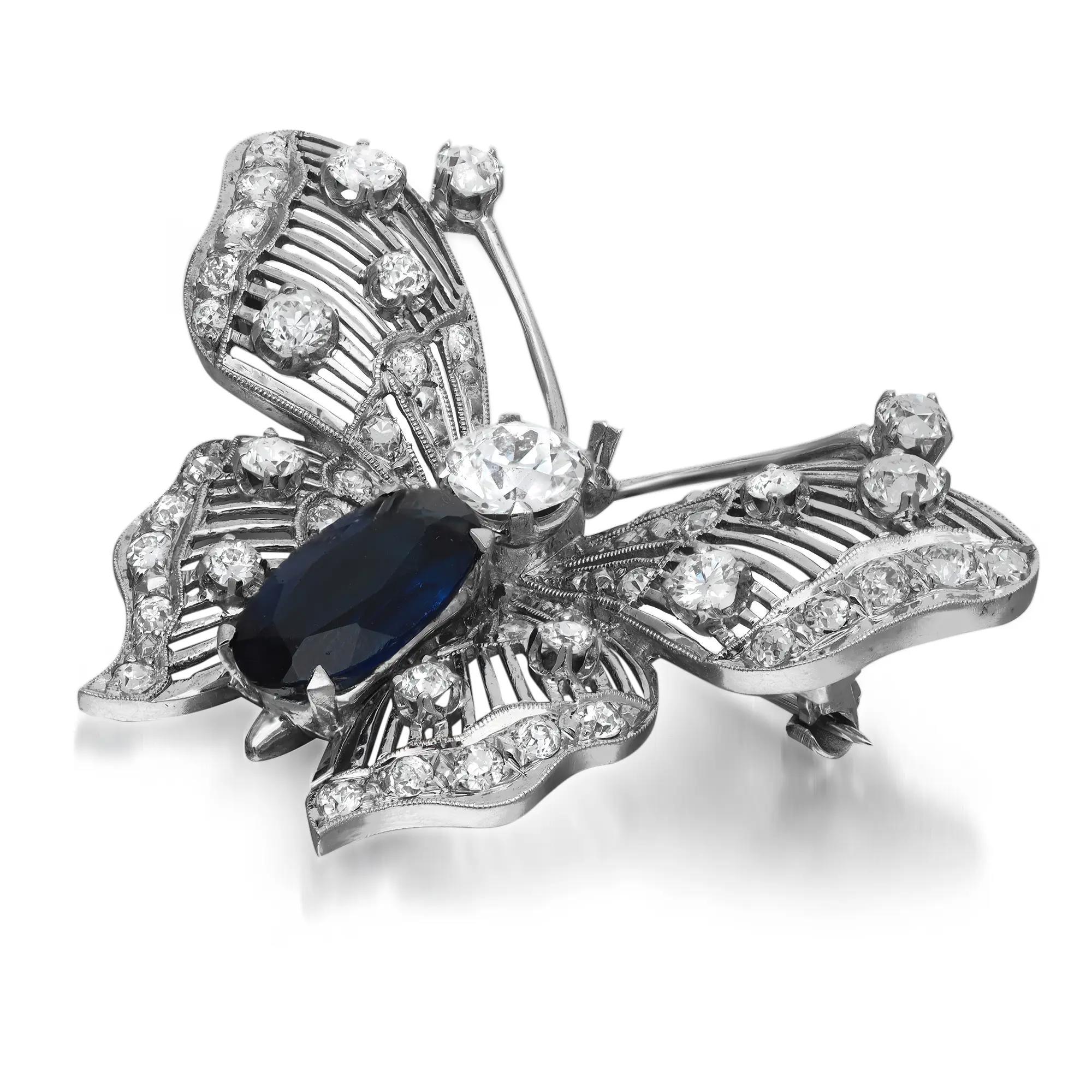 This stunning vintage butterfly brooch is crafted in 14k white gold. It features prong and pave set sparkling round cut diamonds with prong set oval cut synthetic blue sapphire encrusted in an intricate openwork butterfly design. Total diamond