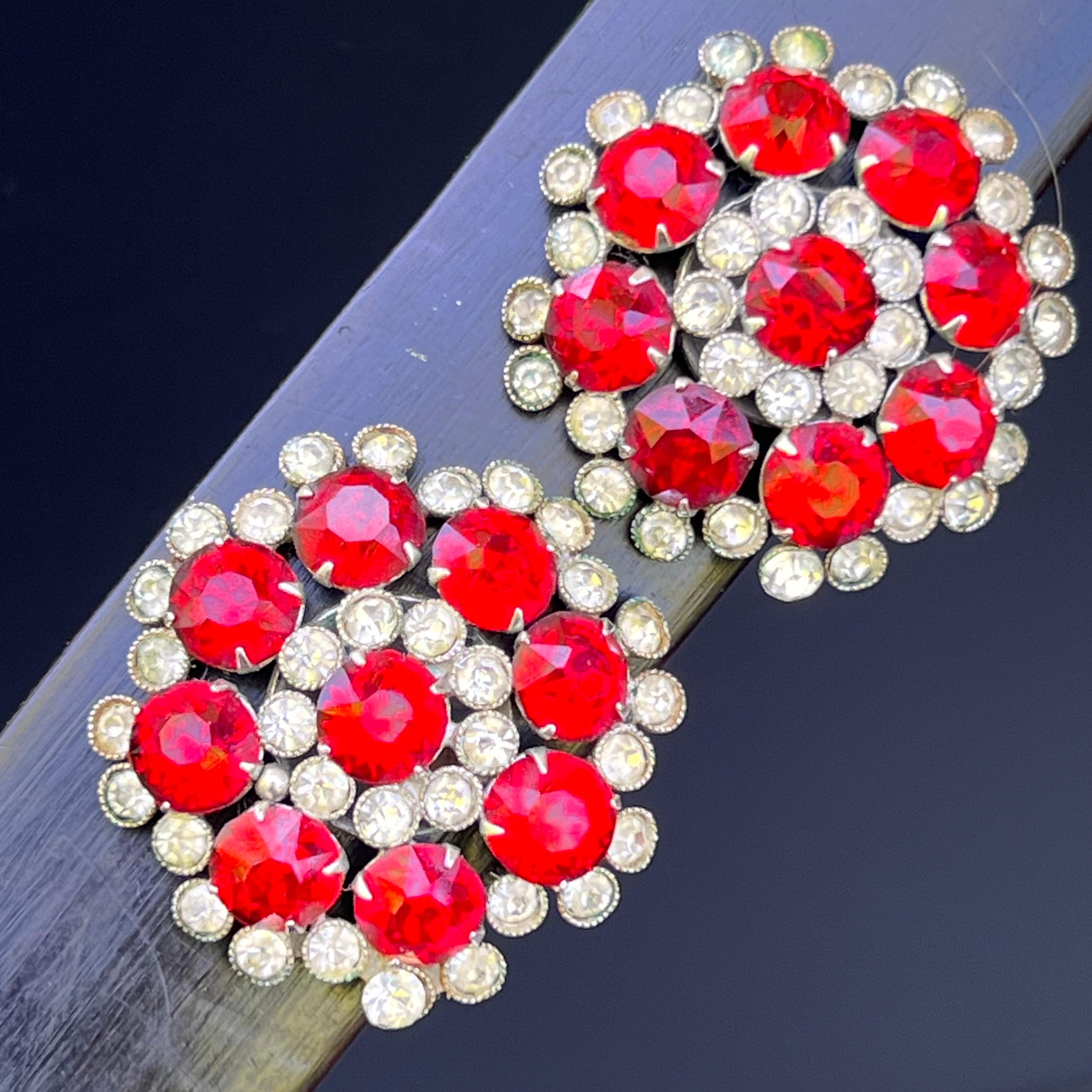 These vintage clip-on earrings from the 1960s feature a striking round lipstick red glass crystal design in a bold flower motif, exuding the glamour and playfulness of mid-century fashion. The vibrant red crystals catch the light beautifully,