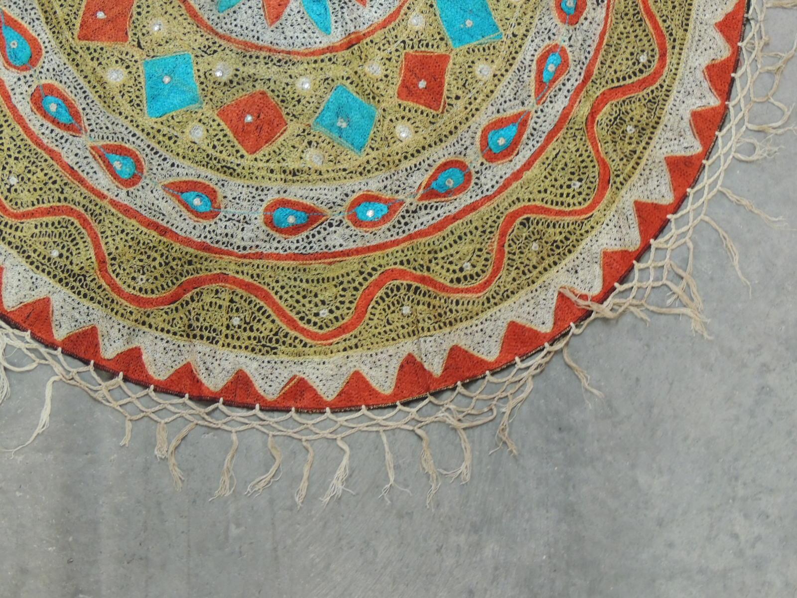 Vintage round orange and turquoise Suzani embroidered table topper with woven knotted fringes.
Size: 39