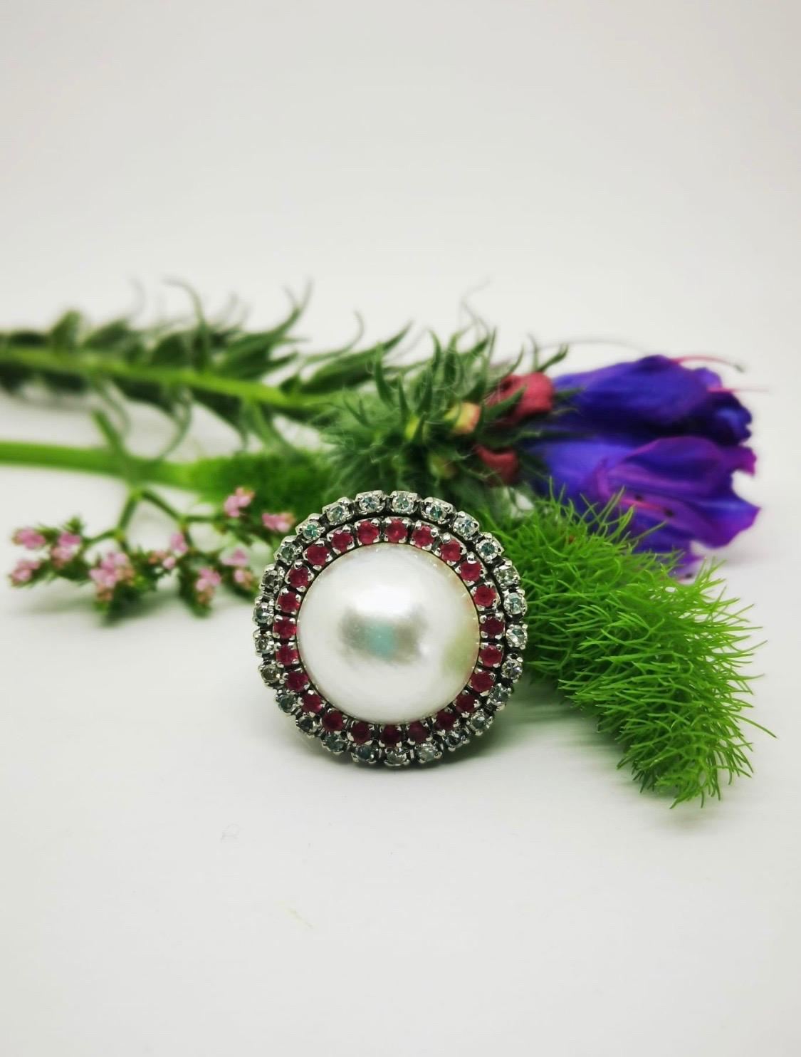 Vintage Pearl, Rubies and  Diamonds Ring

This classic elegant vintage 18k white gold ring with a very beautiful pearl Mabe 15mm diameter surrounded by 23 rubies and 25 diamonds.
Top is the ring measures 22mm by 22mm and shank measures 2mm.

Size