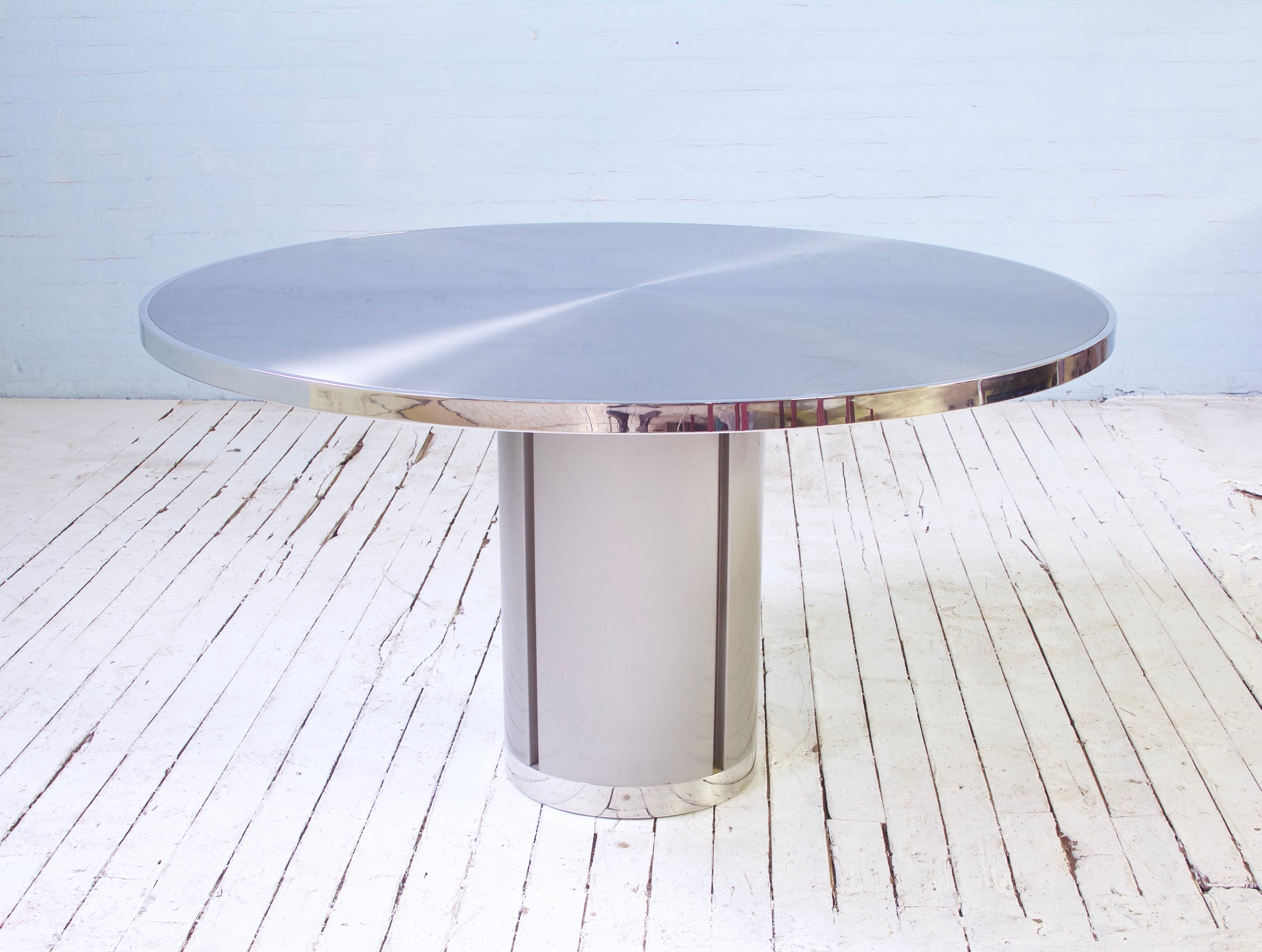 Attractive and useful pedestal-base dining table comprised of brushed aluminum, polished chrome accents, and a welded steel frame with counterweighted base. There is no bad angle on such a minimal, timeless design. Table has been photographed with a