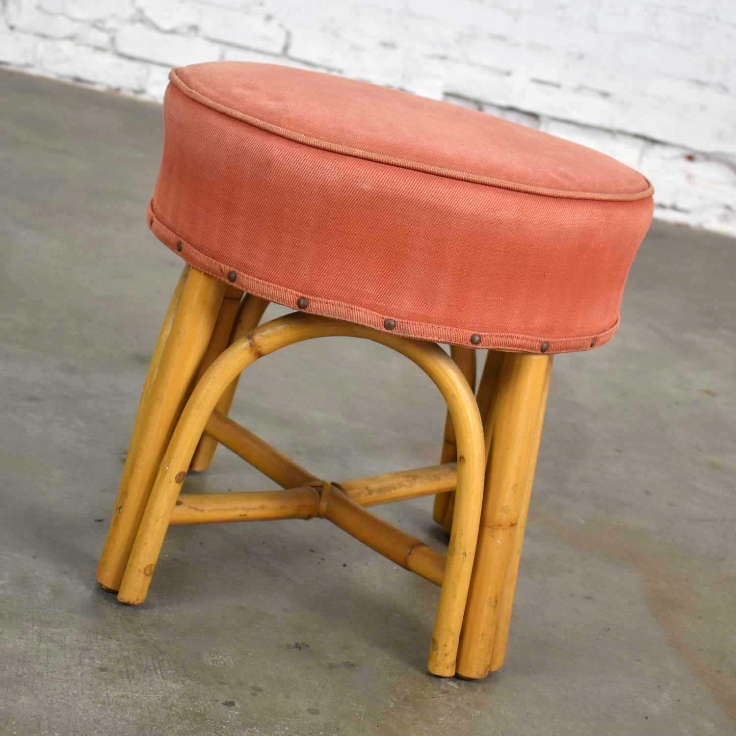 Handsome low foot stool, ottoman, or tuffet in its original upholstered top of perfectly faded terracotta colored gaberdine. It is in wonderful vintage condition. We have restored the rattan finish and shampooed the upholstered top. We love its