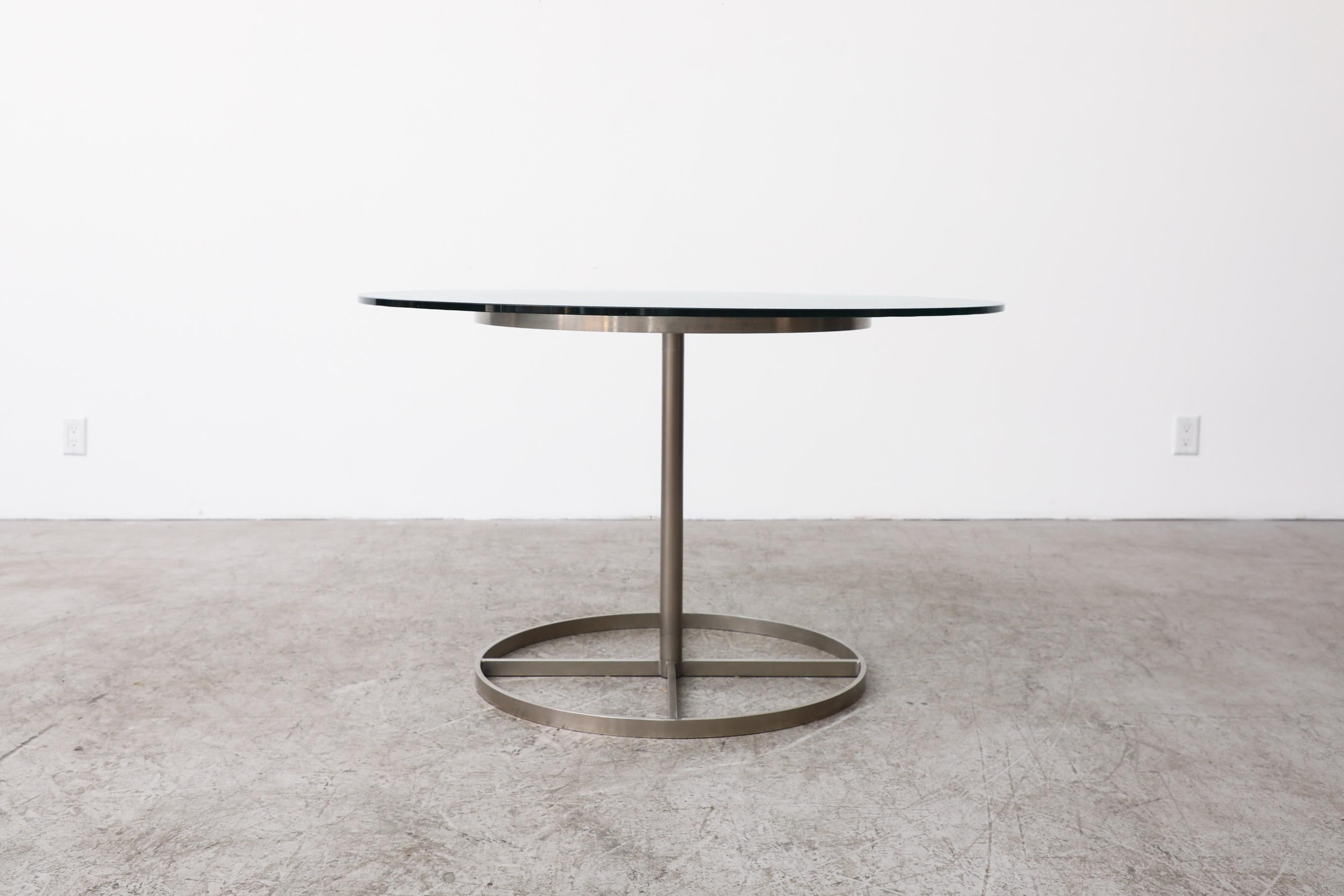 This round dining table has a solid steel base with x design inside and textured glass top. In original condition with visible wear consistent with its age and use.