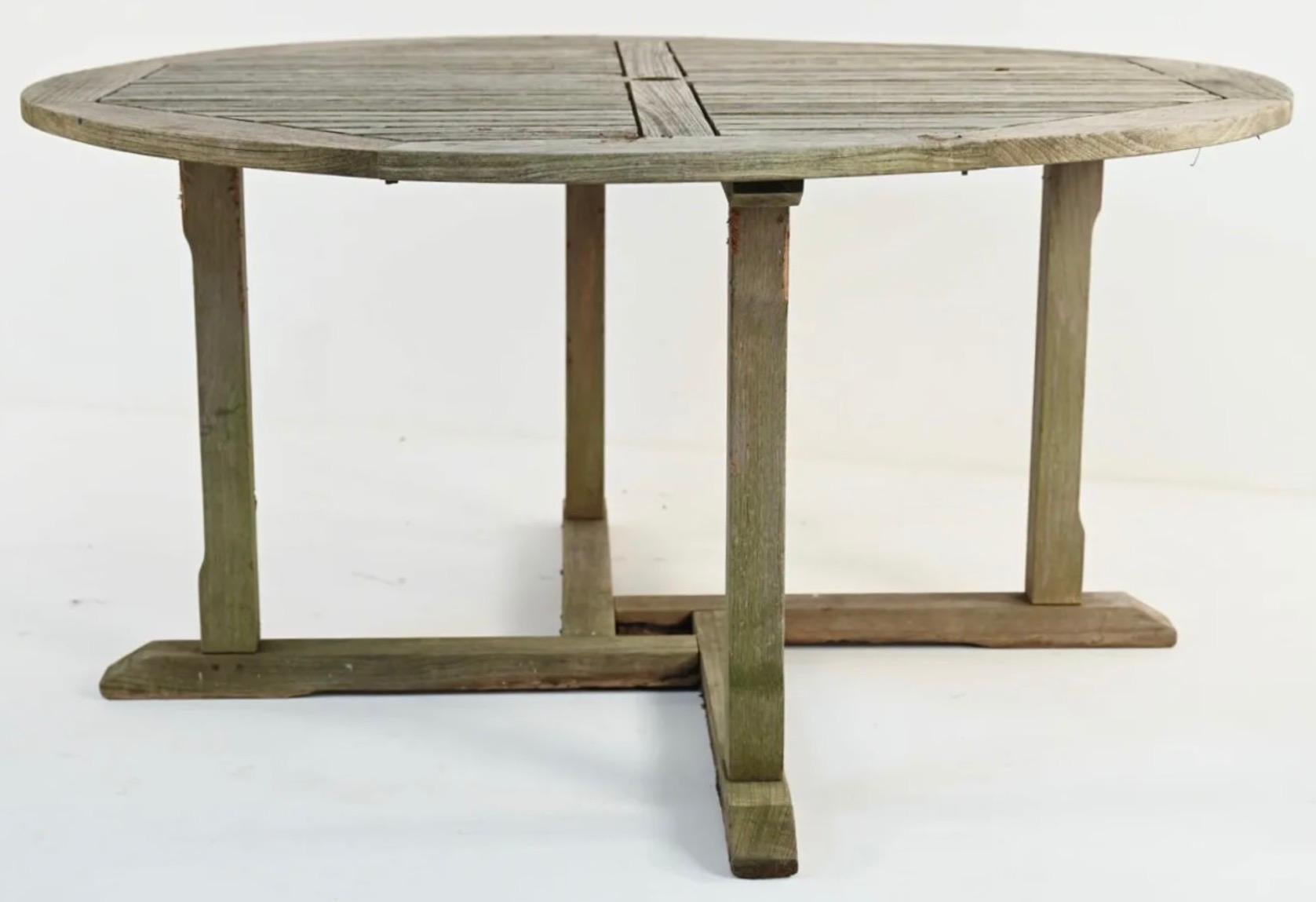 Vintage outdoor round teak wood garden, porch or patio dining table with center hole for umbrella.
 