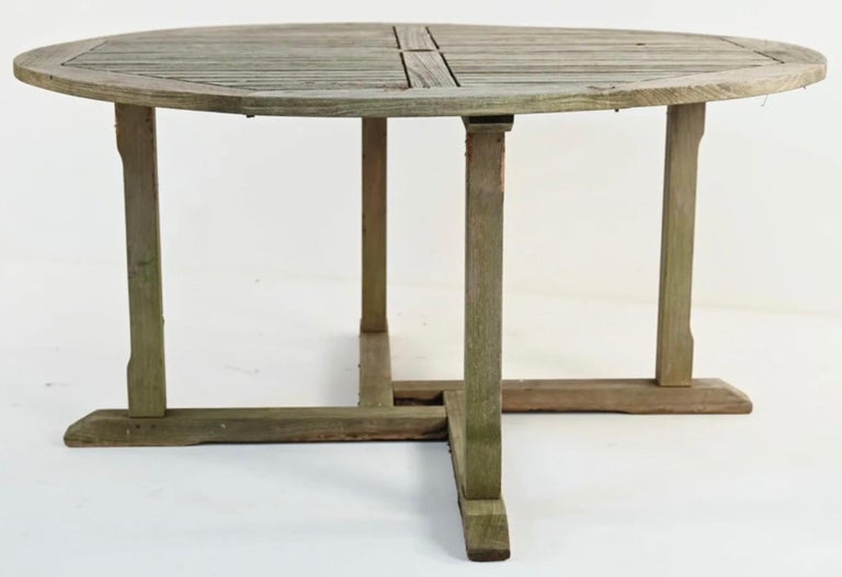Vintage outdoor round teak wood garden, porch or patio dining table with center hole for umbrella.
 