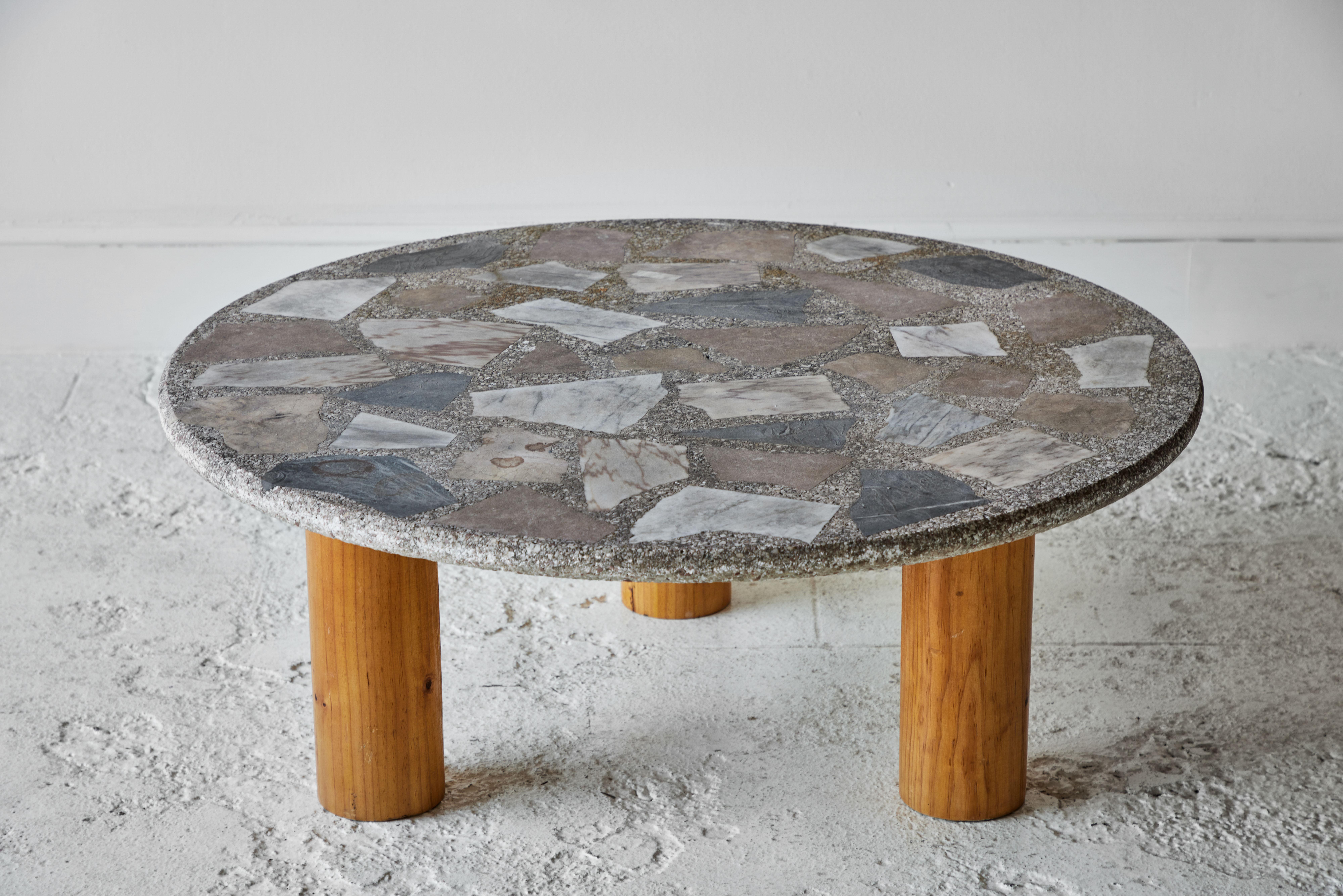 Vintage round terrazzo table sits on top of a three cylindrical legged oak base.