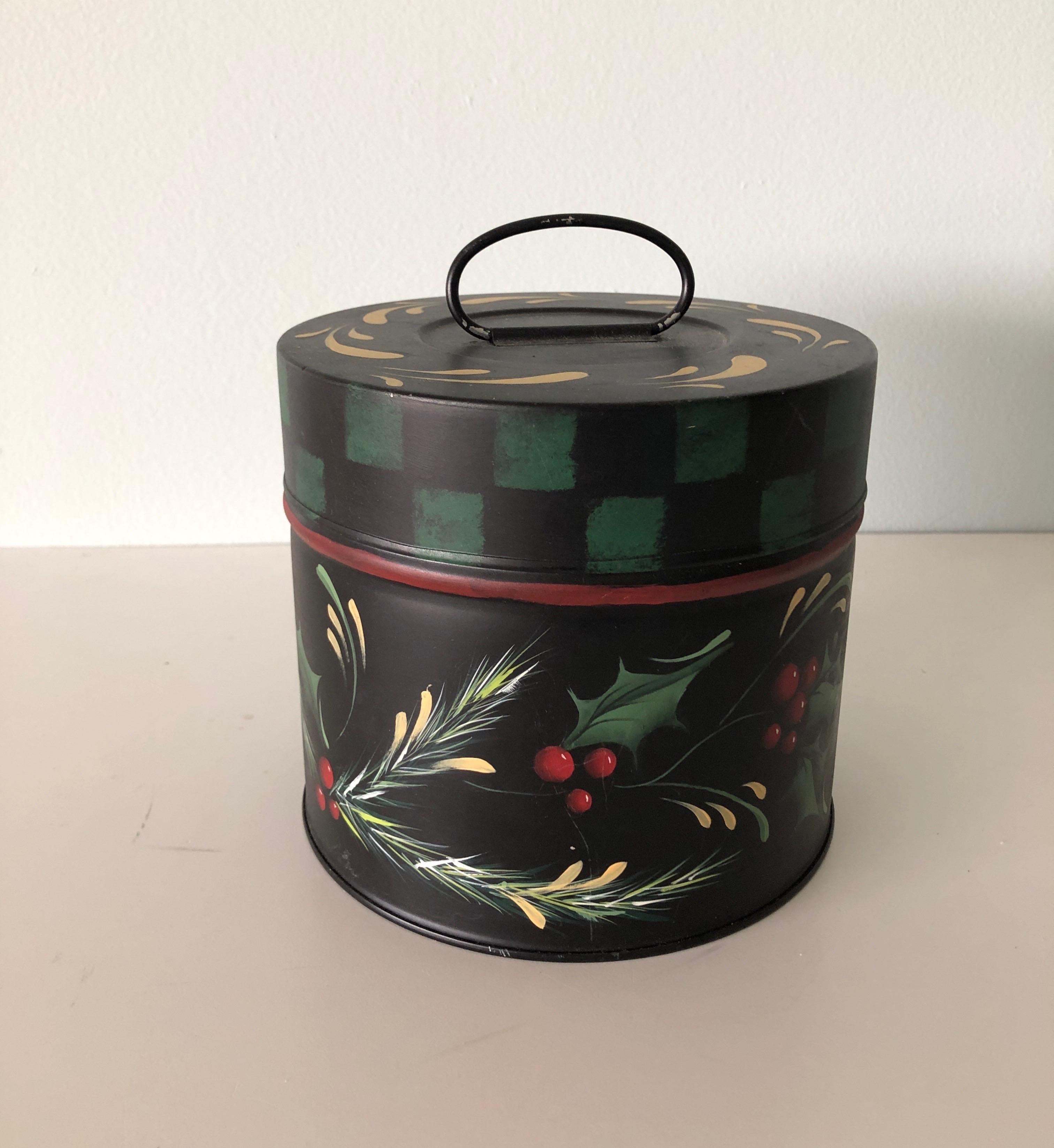 Vintage round tole hand painted canister with holiday theme hand painted details
Depicting vine and berries in the classic holiday colors of green, gold and red. 
Stamped by Sayso, 1996.
Hand painted canister with a handle and finished on all