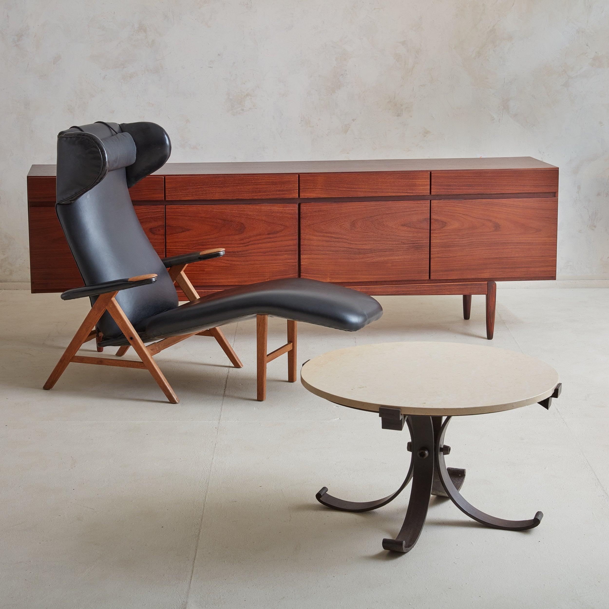 Cette table basse française vintage présente un plateau rond en travertin adouci d'une belle teinte crème avec de délicates veinures pêche et blanc cassé. La Nature repose sur un socle en fer avec quatre pieds cannelés qui s'incurvent élégamment et