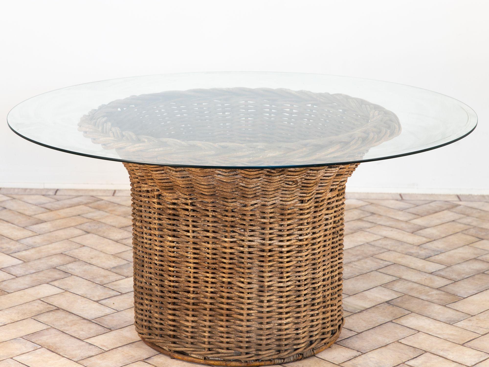 A vintage French 1960s round side table featuring a woven wicker pedestal base topped with a clear round glass surface. The cylindrical wicker base is crafted with a tight, uniform weave, accented at the top with a bold braided rim detail visible