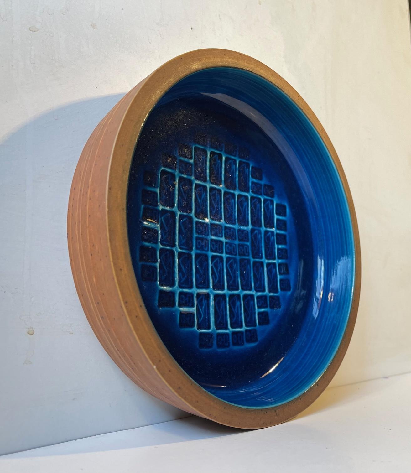 Ein seltener Teller oder eine Schale des dänischen Keramikers Jørgen Mogensen. Außen aus unglasiertem Steinzeug und innen mit abstrakten Mustern, die durch eine leuchtend blaue Glasur hervorgehoben werden. Vom Künstler handsigniert und