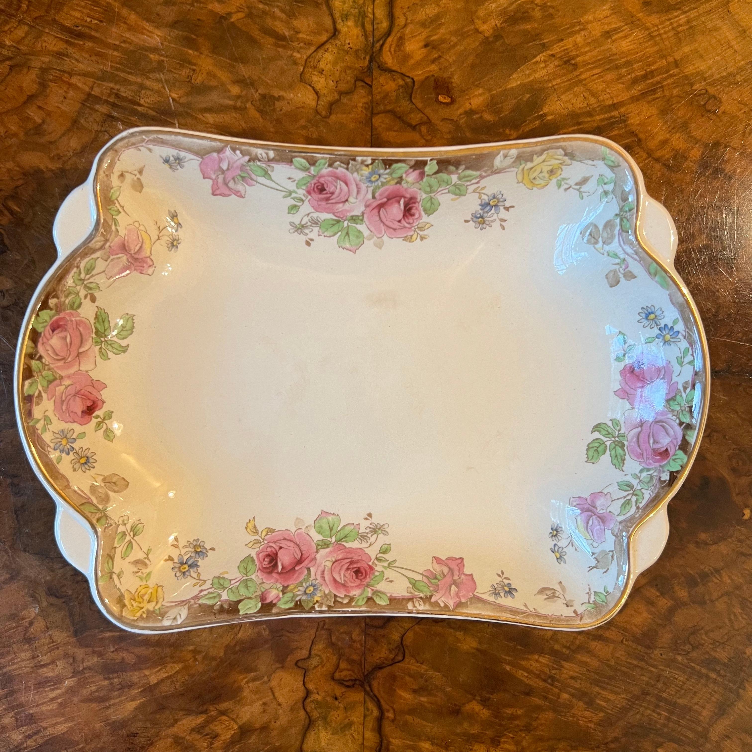 Pink roses print with green leaves and gold trimming, some ware to gold trim, crazing, stamped Royal Doulton English Rose

Circa: 1930s

Material: Porcelain 

Country Of Origin: England

Measurements: 3cm high, 23.5cm length, 16cm width