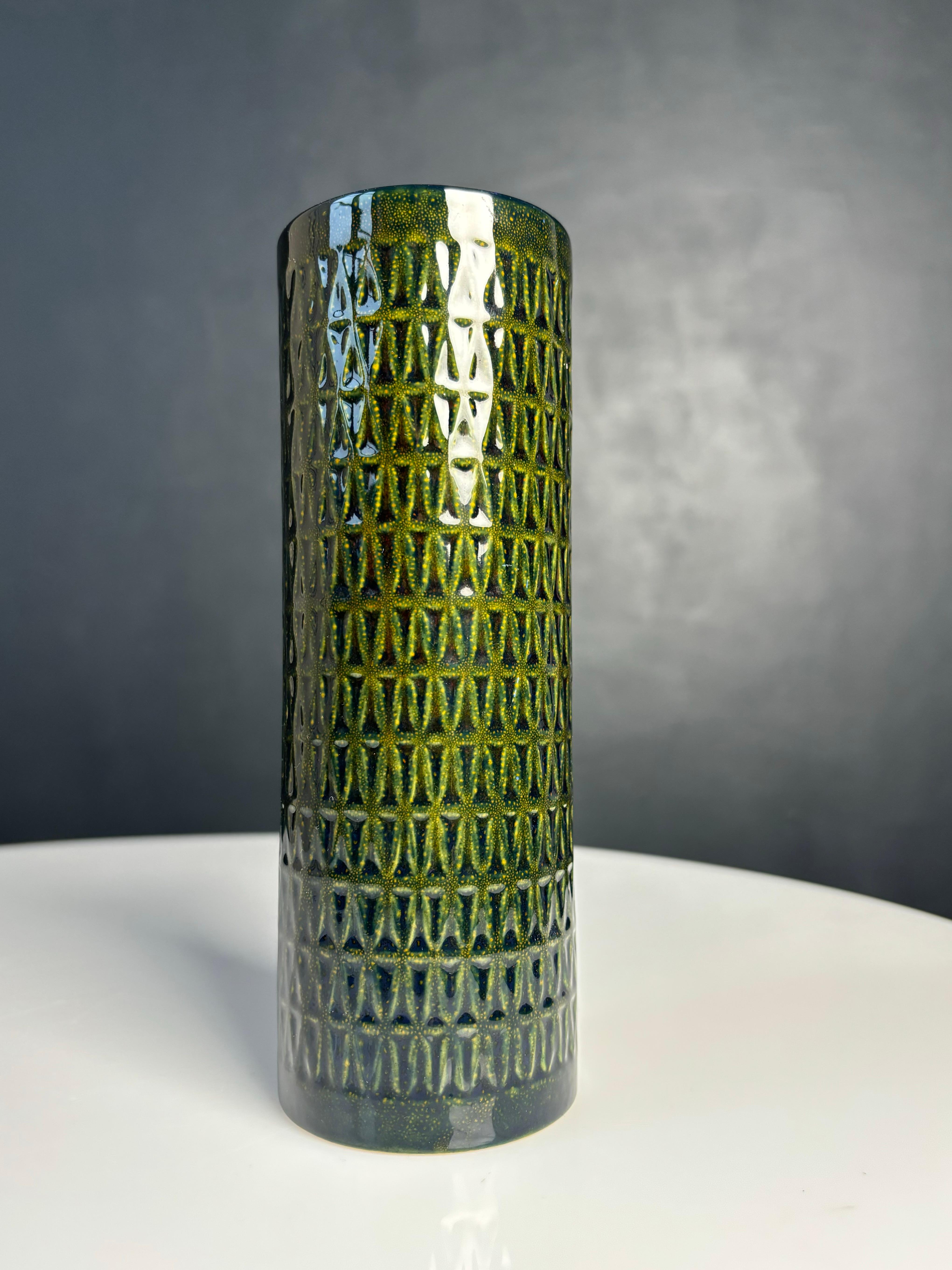 Olivgrüne und dunkelbraune zylinderförmige Vase, hergestellt von Royal Doulton in den 1970er Jahren. Texturiertes grafisches Reliefmuster unter der glänzenden erdfarbenen Glasur.
Unter dem leuchtend rot glasierten Sockel gestempelt. Schöner