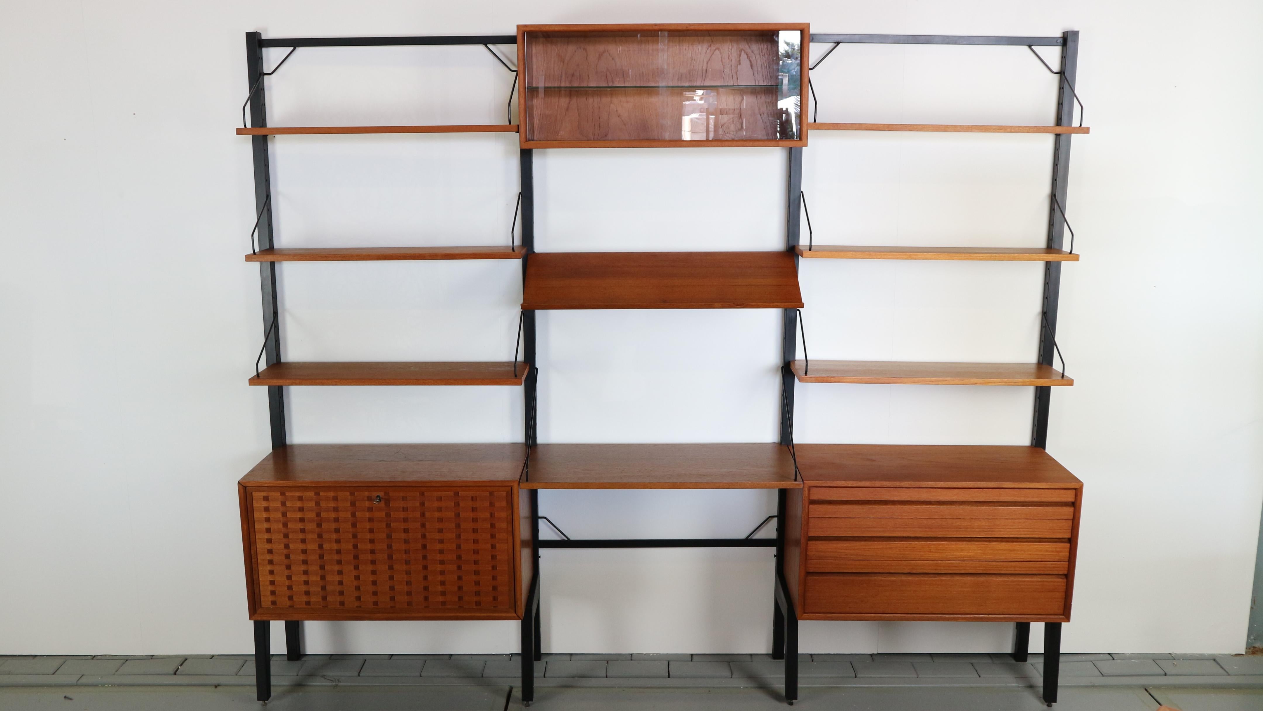 Original freestanding wall unit designed by Poul Cadovius, model Royal, in the 1950s for Cado, Denmark. This listed unit was produced by Cado in Denmark in the 1960s. The elements features a lovely quality teak veneer and four metal uprights who can