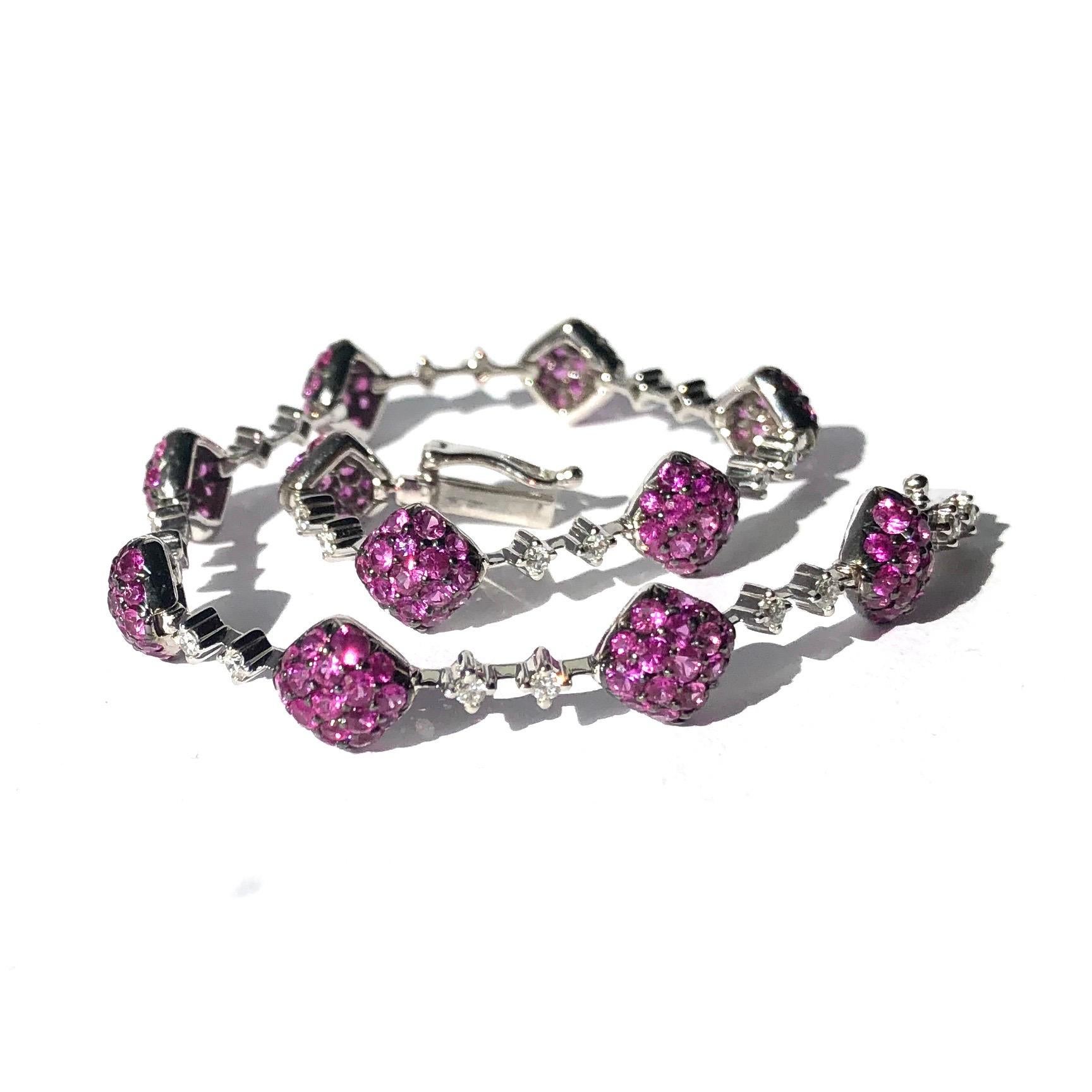This show stopping bracelet is adorned with glittering deep pink rubies. The rubies are set within cushion panels which are connected by a link that also holds two diamonds as well as the clasp. Each ruby ranges in size from 2-4pts and there are a