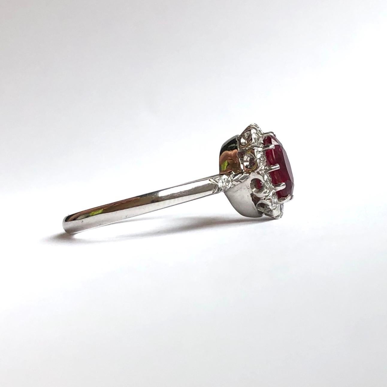 At the centre of this gorgeous cluster there sits a bright red ruby measuring 1.06carat and it is surrounded by bright sparkly diamonds and also hold a diamond on each shoulder. The diamonds total approx 20pts. Modelled in 18ct white gold. 

Ring
