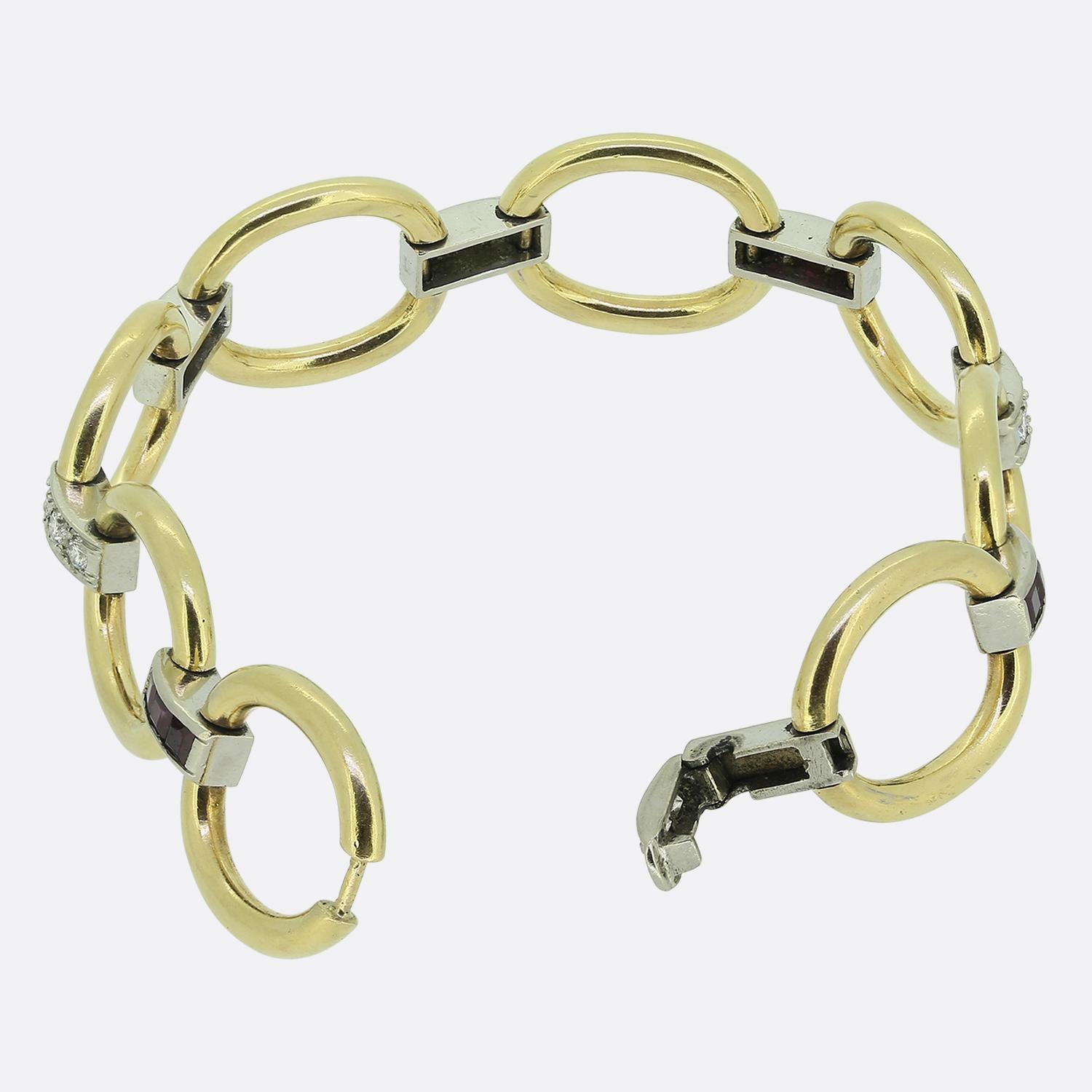 Here we have a delightful bracelet crafted from a combination of 14ct yellow gold platinum. This vintage piece showcases a series of wide open oval links, each connected by a slim platinum accent adorned with either a trio of square-shaped rich red
