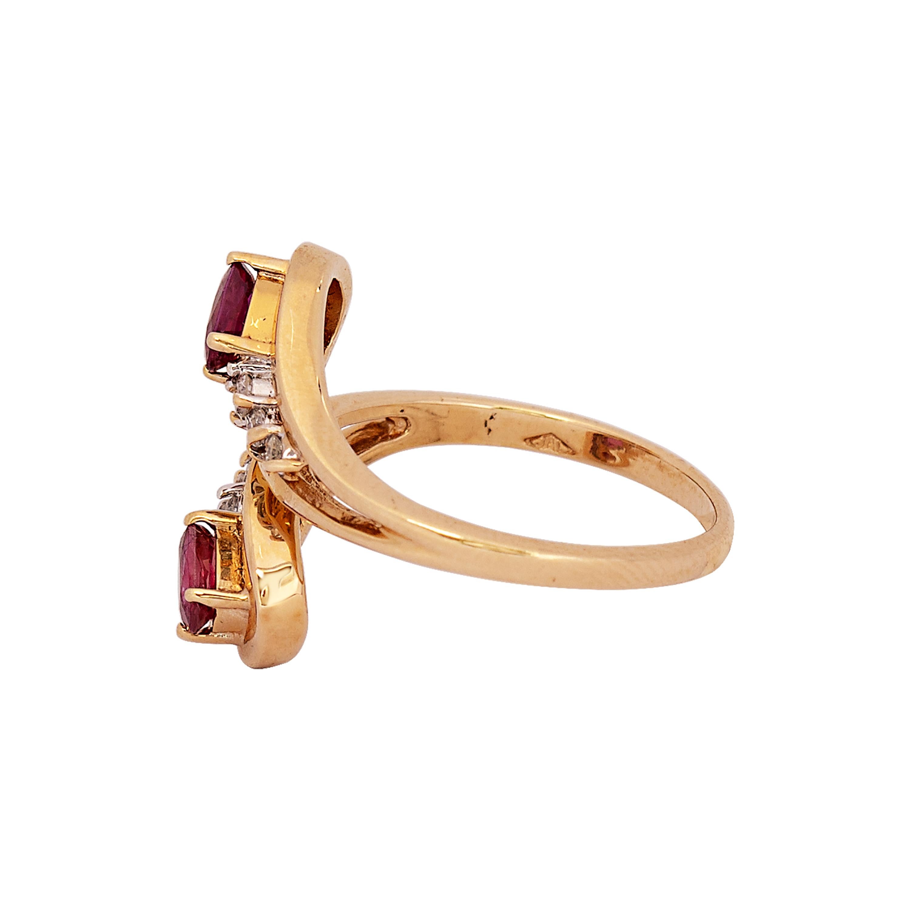 An elegant 14 karat yellow gold bypass ring comprised of graceful open teardrops each terminating in two oval cut rubies trailing a row of three round brilliant white diamonds. Each ruby weighs approximately .25 carats and the six round brilliant