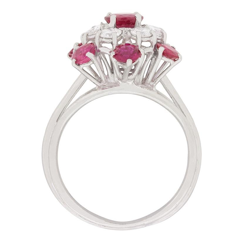 This stunning and breath-taking ring features a total of 2.60 carat's worth of wonderful rubies. The centre stone is 0.60 carat and is expertly claw set. It is then haloed by a circle of round brilliant white diamonds, which is turn are haloed by an