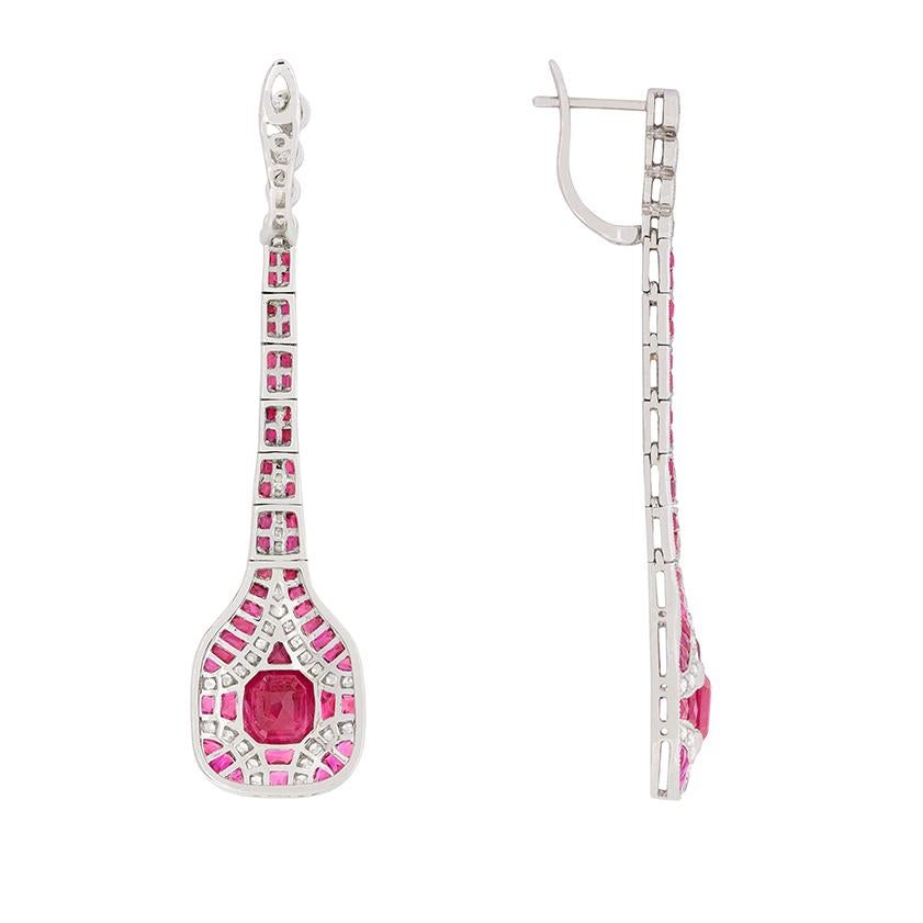 These fabulous earrings date to approximately the 1950s. Crafted from 18 carat white gold, they feature a vintage design of deep red rubies and shining diamonds. In the centre of each earring is a ruby weighing 1.70 carat and the rest of the french