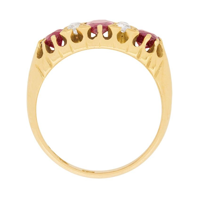 This vintage 1970s era ring is set in hand-engraved 18 carat yellow gold with an enticing combination rubies and diamonds. A deep red, faceted, oval-shaped ruby set at the ring’s centre is flanked to either side by a pair of round brilliant cut