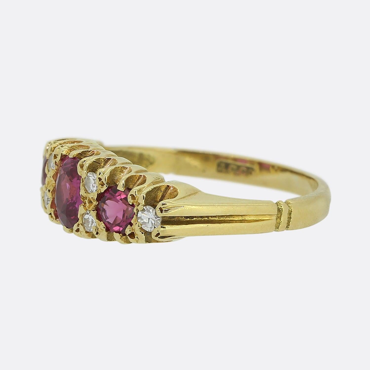 Here we have a classic styled three-stone ruby ring. This vintage piece showcases a single oval faceted ruby a the centre of the face which is flanked on either side by a single slightly smaller round shaped ruby. Each ruby exhibits a perfectly