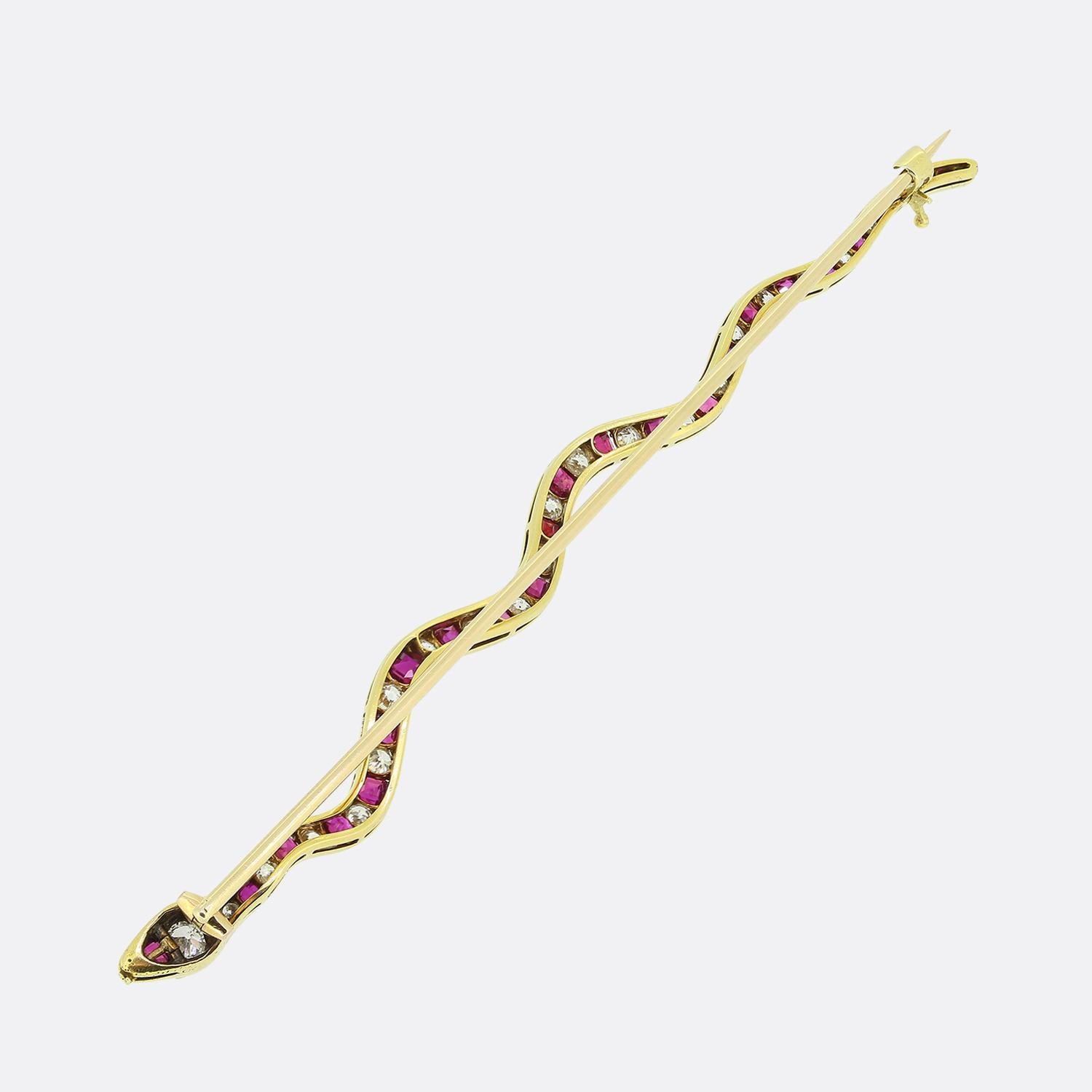 Ecco una squisita spilla con un sinuoso disegno a serpente realizzato in oro giallo 18ct. Il corpo del serpente è ornato da un'alternanza di rubini rossi a taglio quadrato e diamanti bianchi a taglio di vecchia miniera, che creano un contrasto