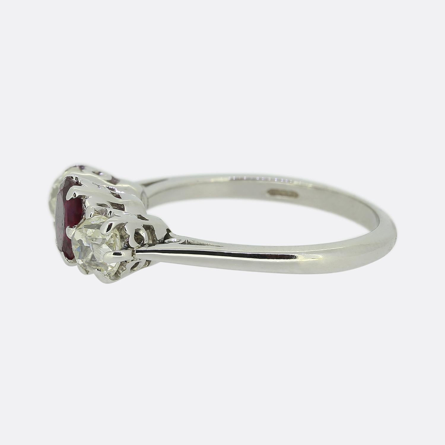 Here we have a delightful ruby and diamond three-stone ring. This vintage piece has been crafted from 18ct white gold and features trio of precious gemstones. An oval faceted  rich red vivid ruby sits boastfully at the centre of the face and is
