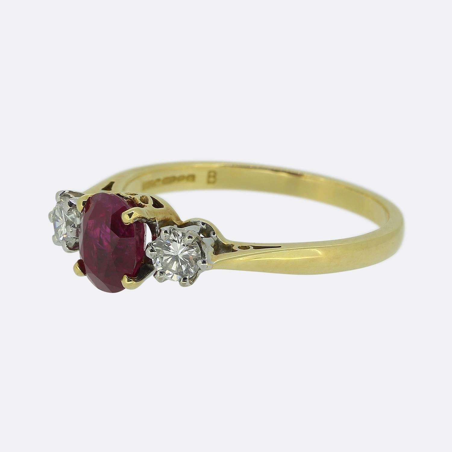 Nous avons ici une bague à trois pierres de style classique. Cette pièce vintage est ornée d'un rubis d'un rouge éclatant, flanqué de deux diamants ronds de taille brillant d'un blanc éclatant. Le rubis est solidement serti dans une monture à quatre