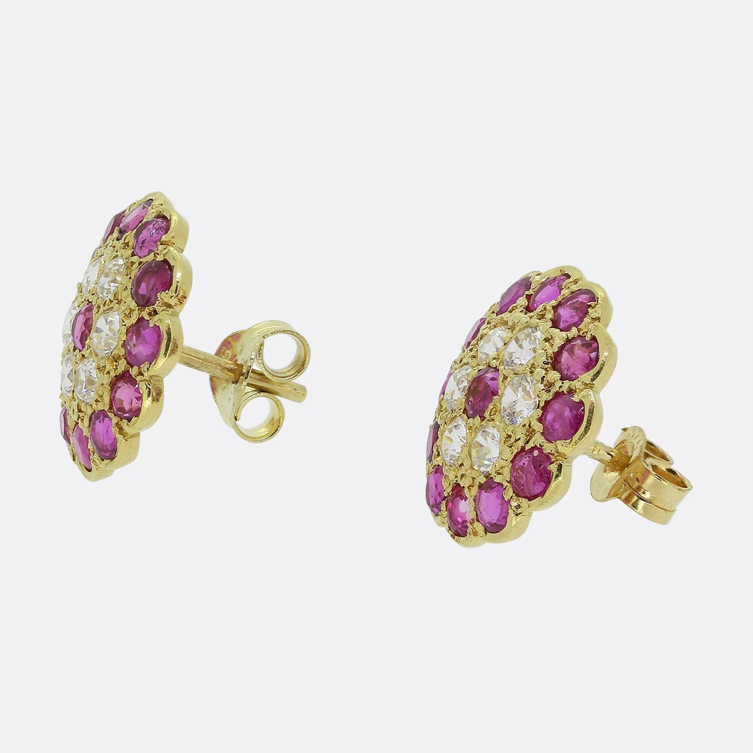 Here we have a stunning pair of ruby and diamond cluster earrings. Each identical piece has been crafted from a rich 18ct yellow gold into a circular shaped with an undulating border around the outer edge containing a central arrangement of round