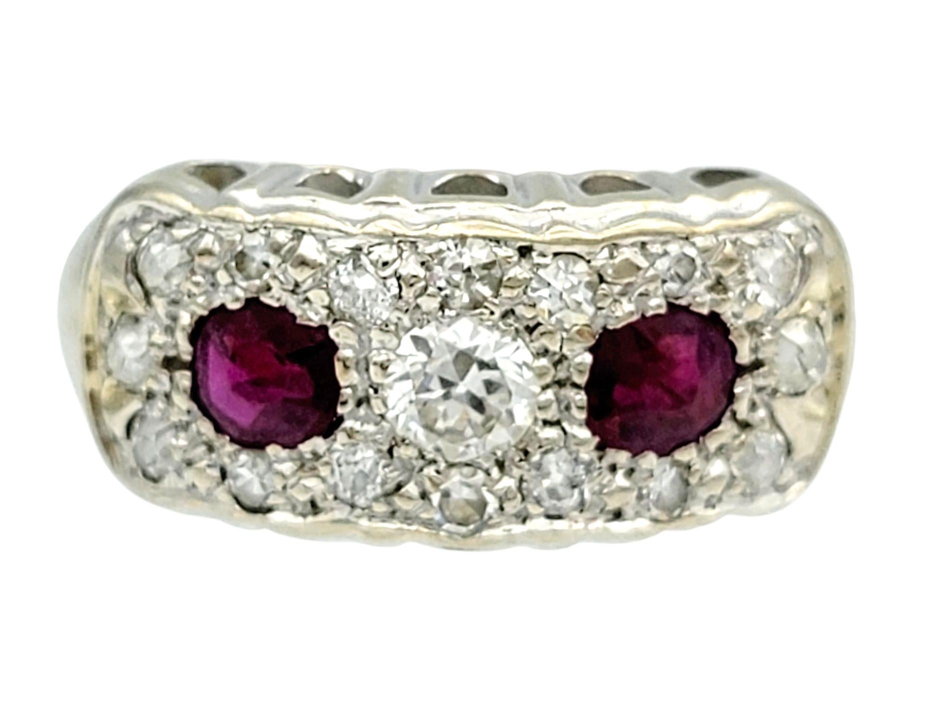 Cette charmante bague vintage présente un équilibre frappant de couleurs et d'éclat, avec deux rubis rouges vifs sertis côte à côte en son centre. Leurs riches tons cramoisis sont encadrés par un motif complexe de diamants étincelants de type Old