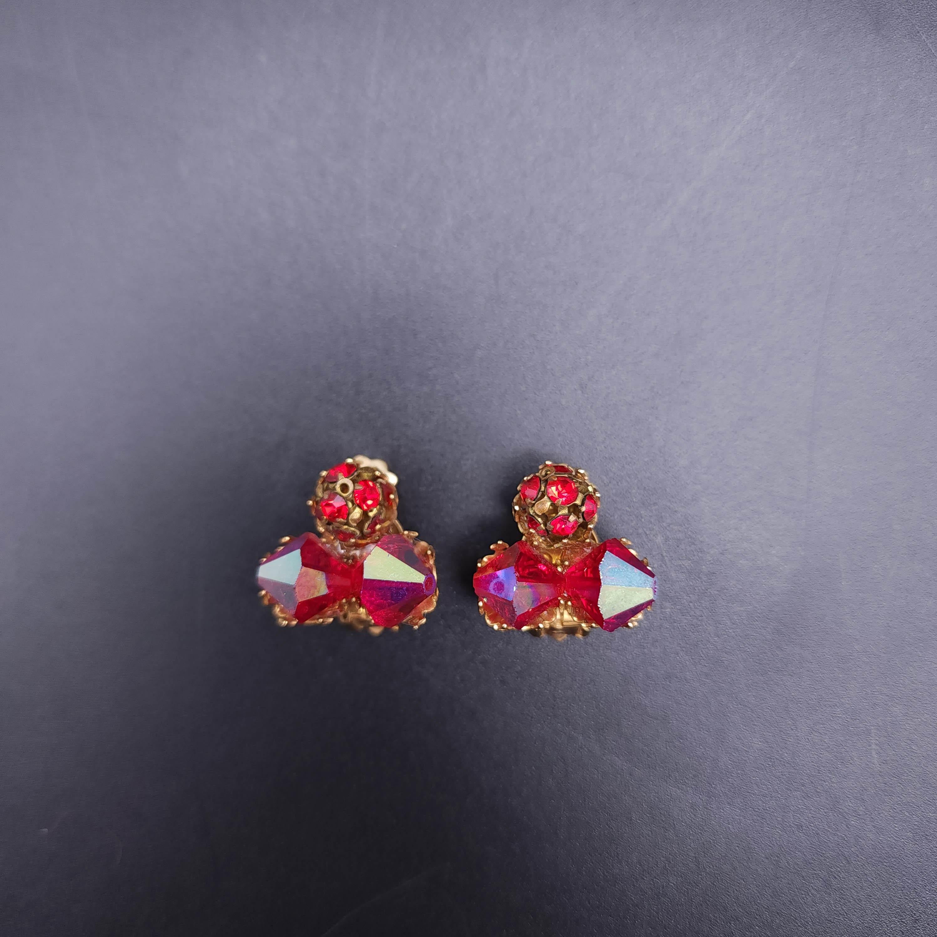 Introducing the enchanting vintage ruby crystal aurora borealis AB clip-on earrings in a stunning gold tone. These earrings are a true vintage treasure, featuring two prong-set crystals that capture the light and sparkle with every movement. At the