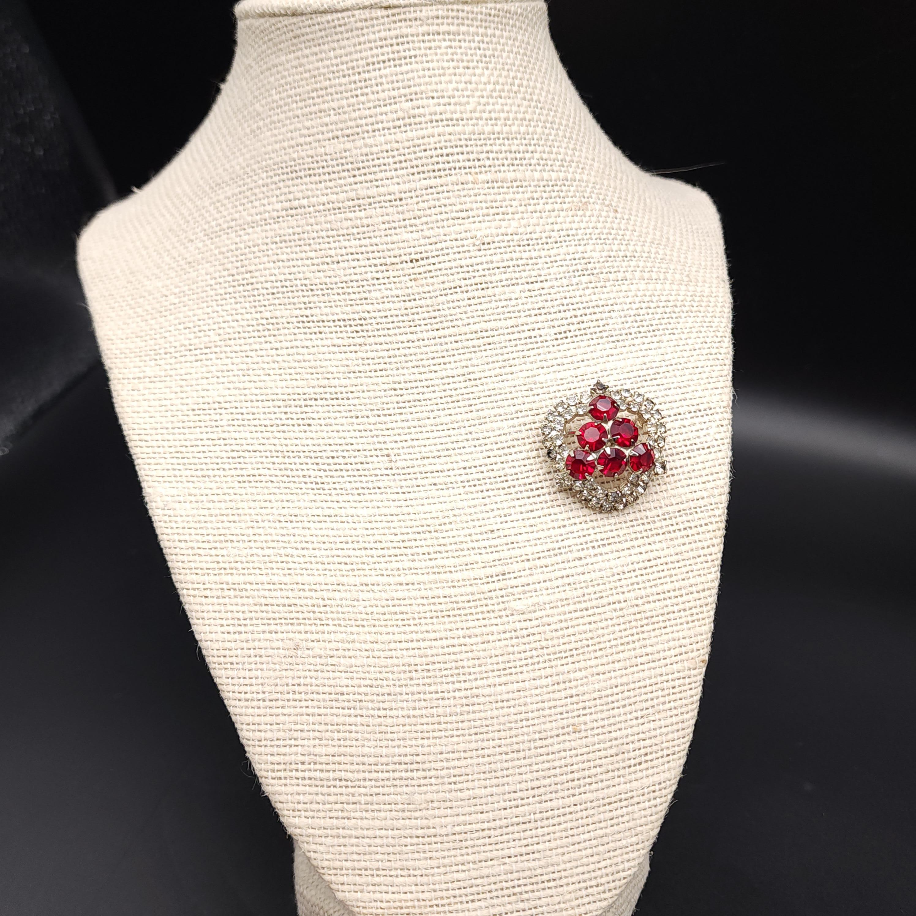 Size: 1 1/8 inches

Discover the elegance of the past with our vintage mid-1900s brooch, featuring a striking triangular pattern of ruby-colored crystals. Each crystal is meticulously prong-set to showcase its brilliance and is complemented by a