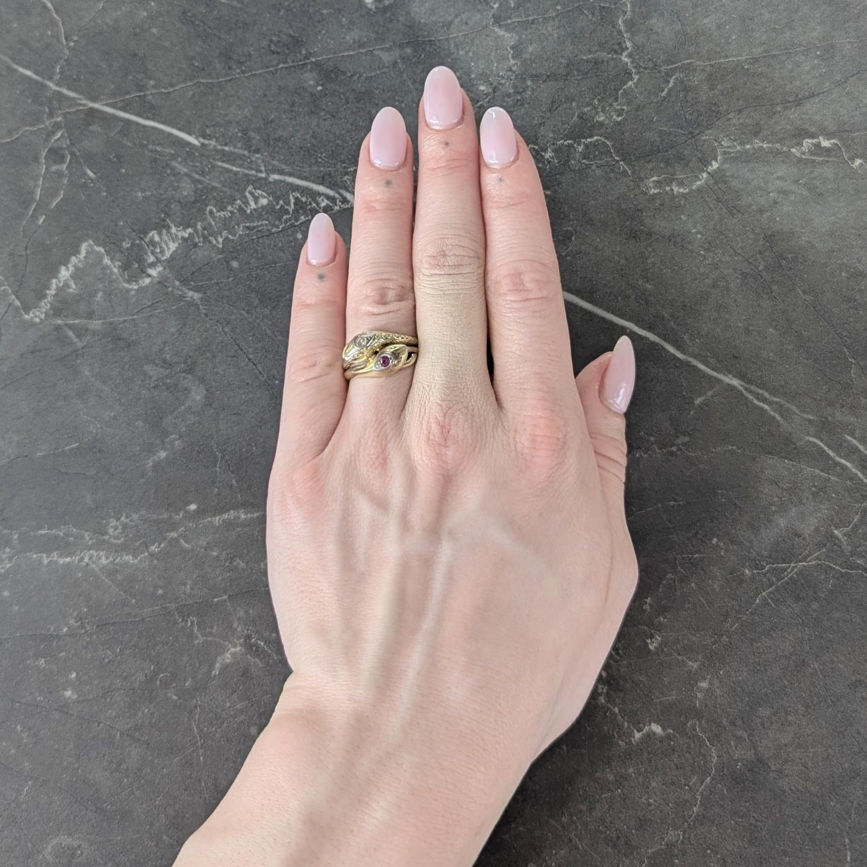 Designed as two entwined snakes with grooved looping bodies and dimensional heads
One head is bead set with a single cut diamond and the other a round cut ruby
Diamond weighs approximately 0.04 carat - H color with VS2 clarity
Ruby weighs