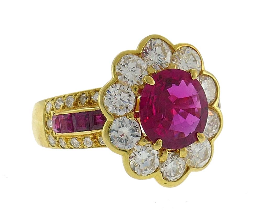 Stunning cocktail ring created in the 1980s. Features a 1.50-carat oval cut ruby framed by ten finest round brilliant cut diamonds, D-E/VS, set in 18 karat yellow gold. The sides of the ring shank are accented with 0.44 carat table cut rubies and