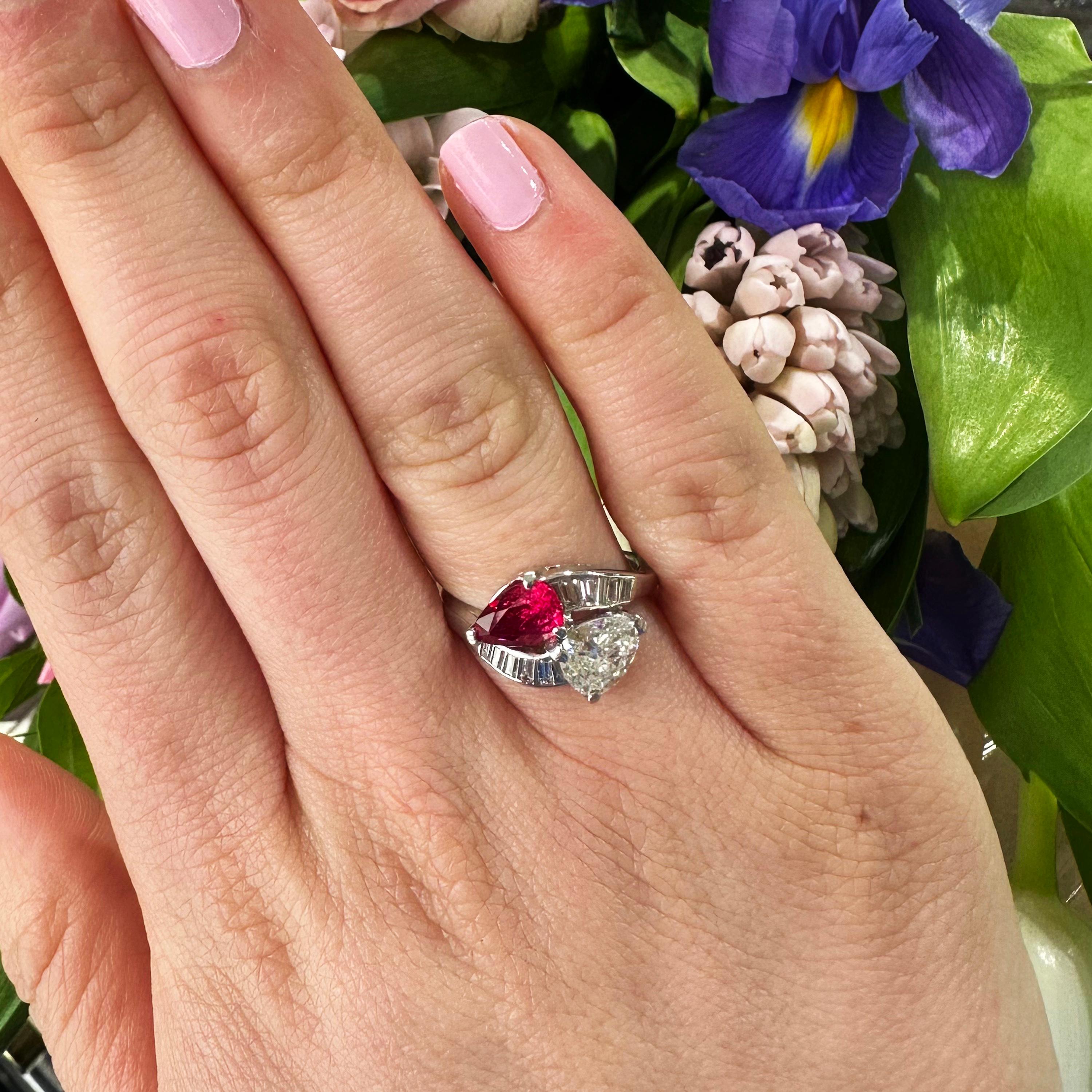 A vintage, hand made, ruby and diamond crossover ring, set with a pear shape ruby, weighing approximately 1.27ct and a pear shape diamond weighing approximately 0.80ct, in claw settings, flanked by baguette-cut diamonds, in channel settings, in each