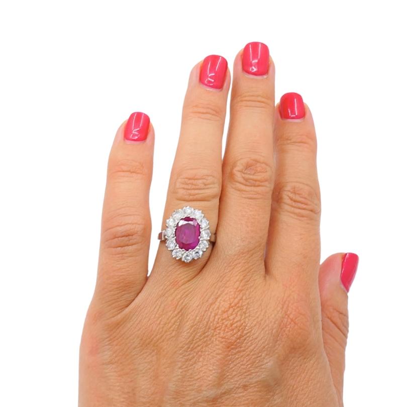 Questo elegante anello a grappolo vintage mette in mostra un vibrante rubino dal taglio ovale, incorniciato da una scintillante aureola di diamanti incastonati in oro 14k. Il rubino centrale cattura l'attenzione con la sua ricca tonalità rossa,